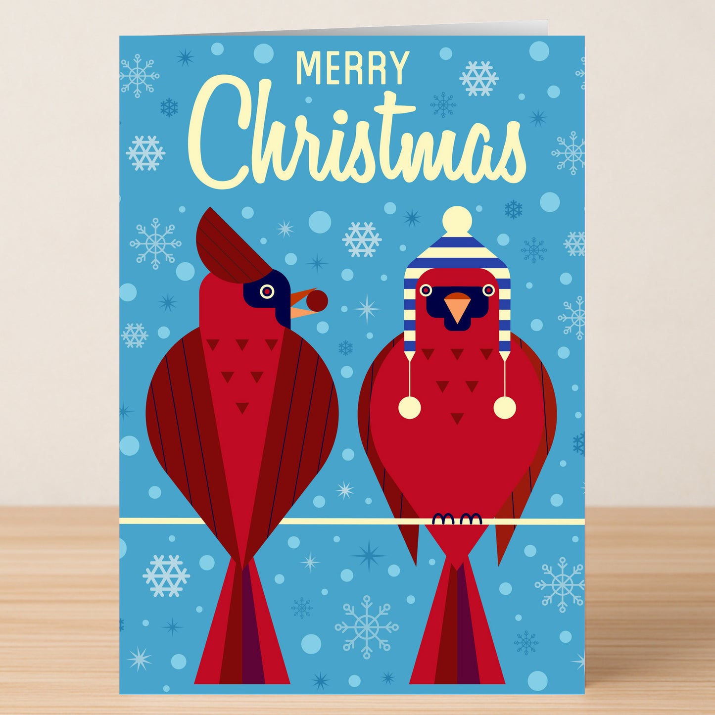 The Twisted Gifts Birds Christmas Card features two red cardinals on a wire—one in a blue and white winter hat—against a blue snowflake background with “Merry Christmas” text, perfect for festive holiday greetings.