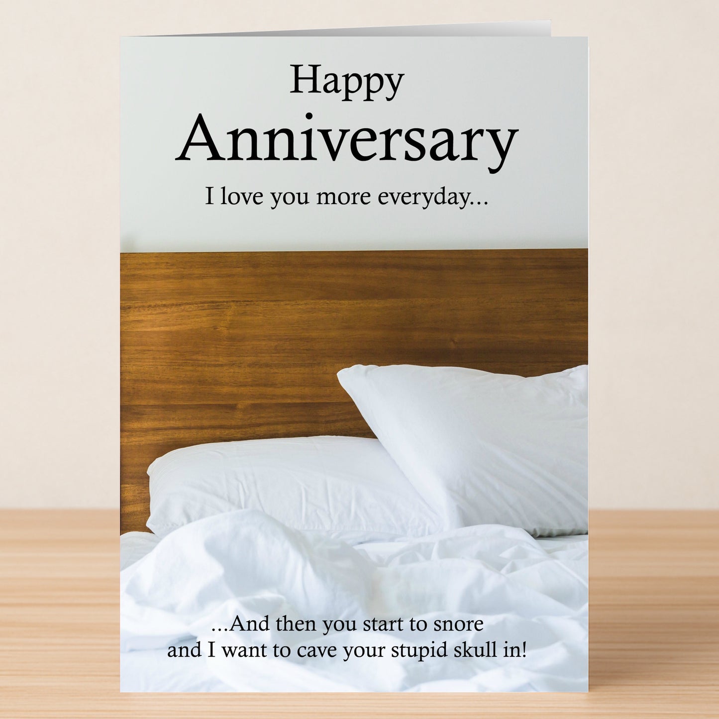 The Snore Funny Anniversary Card by Twisted Gifts features an unmade bed and reads: “Happy Anniversary. I love you more every day… And then you start to snore and I want to cave your stupid skull in!”.