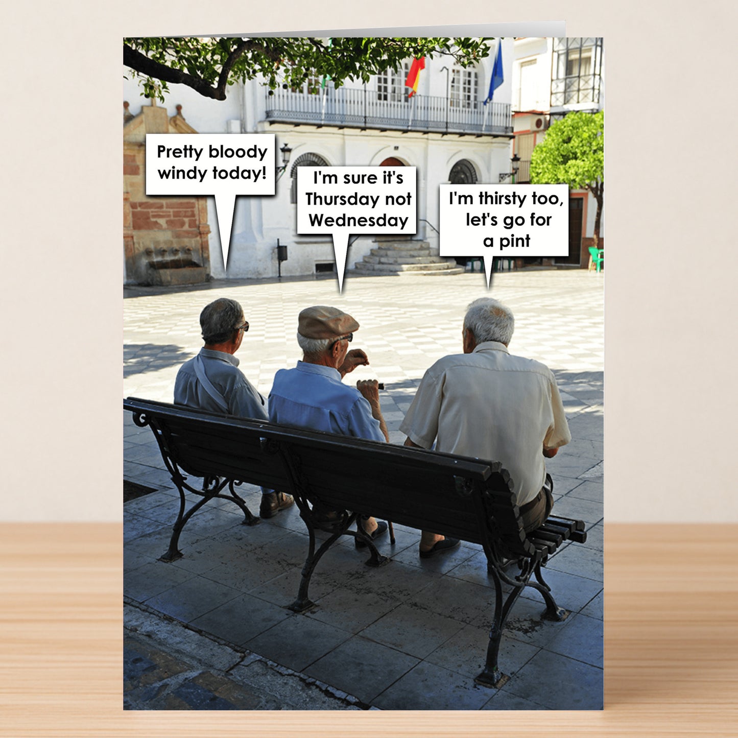 The Windy Thursday Funny Greeting Card by Twisted Gifts shows three elderly men on a sunny bench, cracking jokes about the weather and wishing for a drink—perfect for sending laughs to friends.