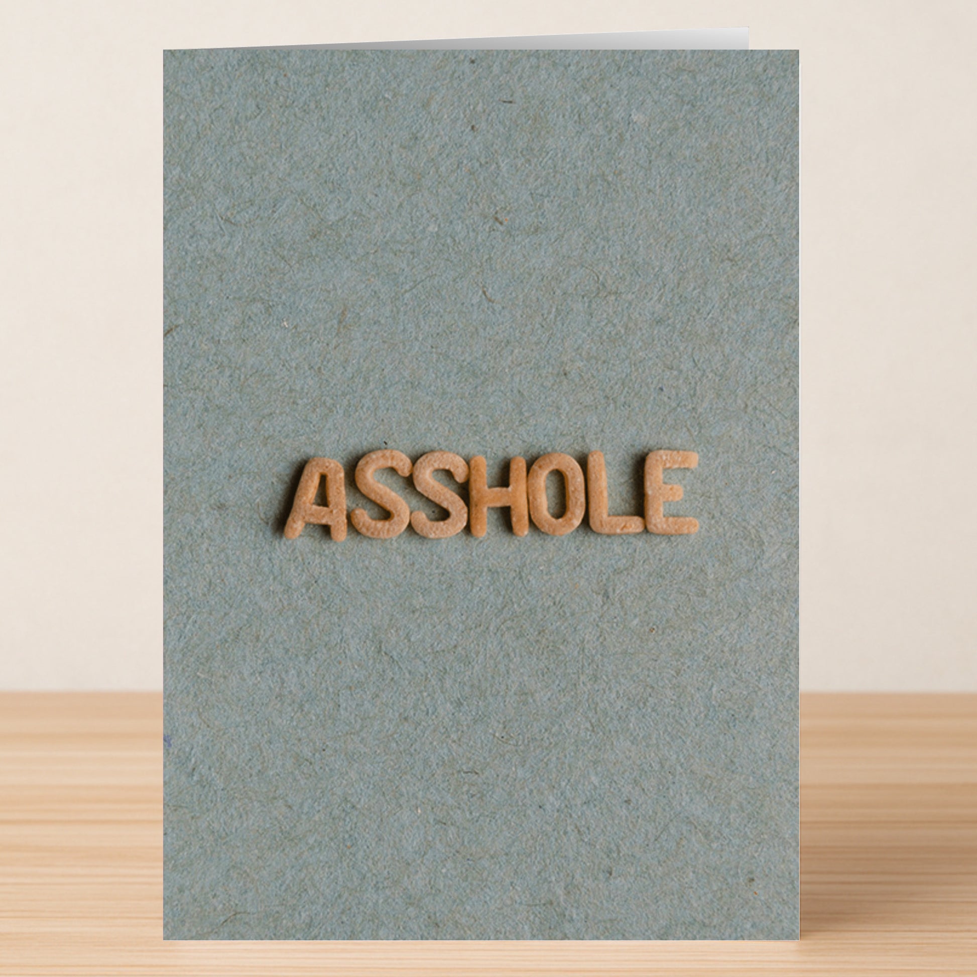 The Twisted Gifts Asshole Insulting Greeting Card features a grey textured design with "ASSHOLE" in brown letters, perfect for anyone with a sassy sense of humor.