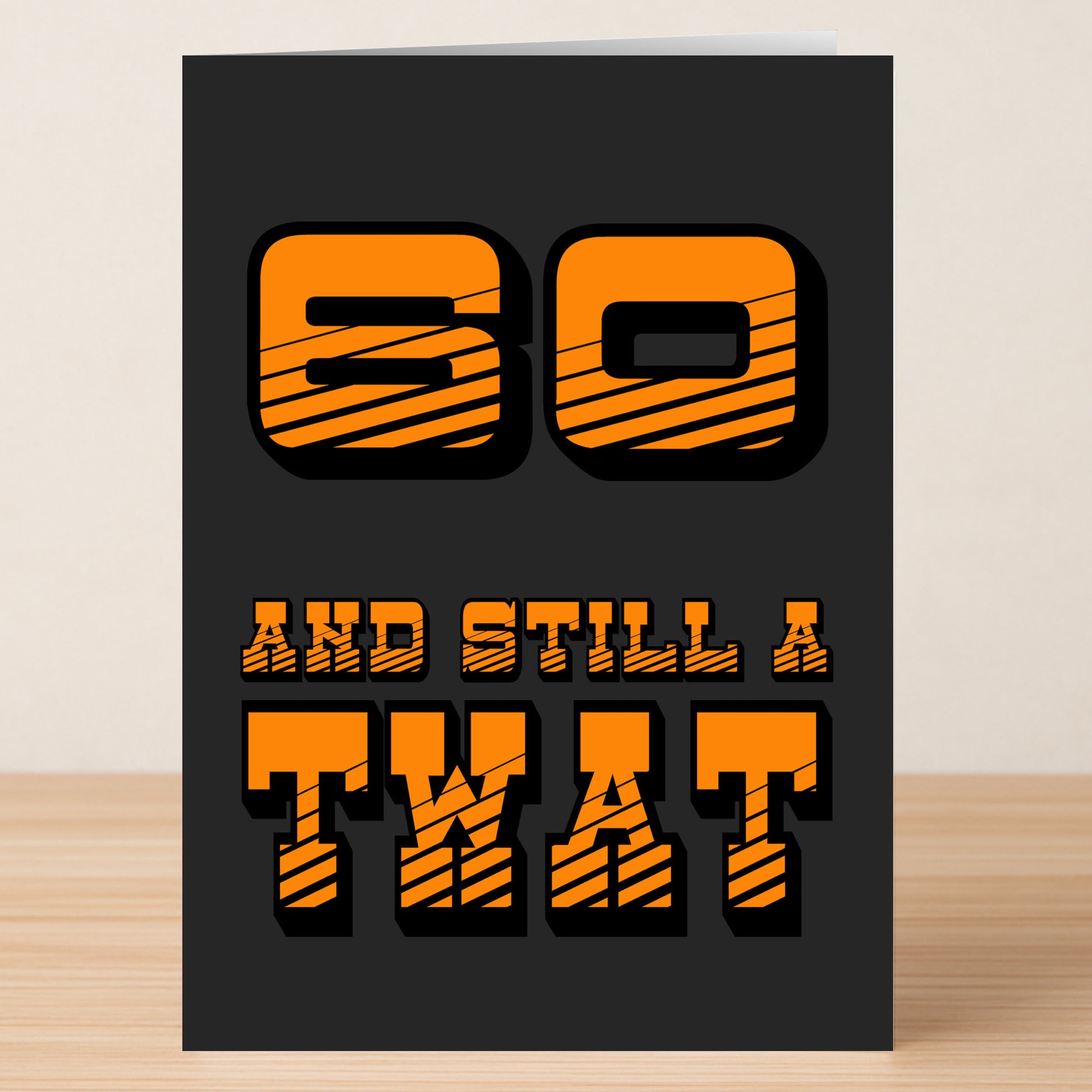 The Twisted Gifts "60 - Still A Twat 60 Insulting Birthday Card" features bold orange text on a black background with a cheeky greeting, perfect for adding humor to a 60th birthday.