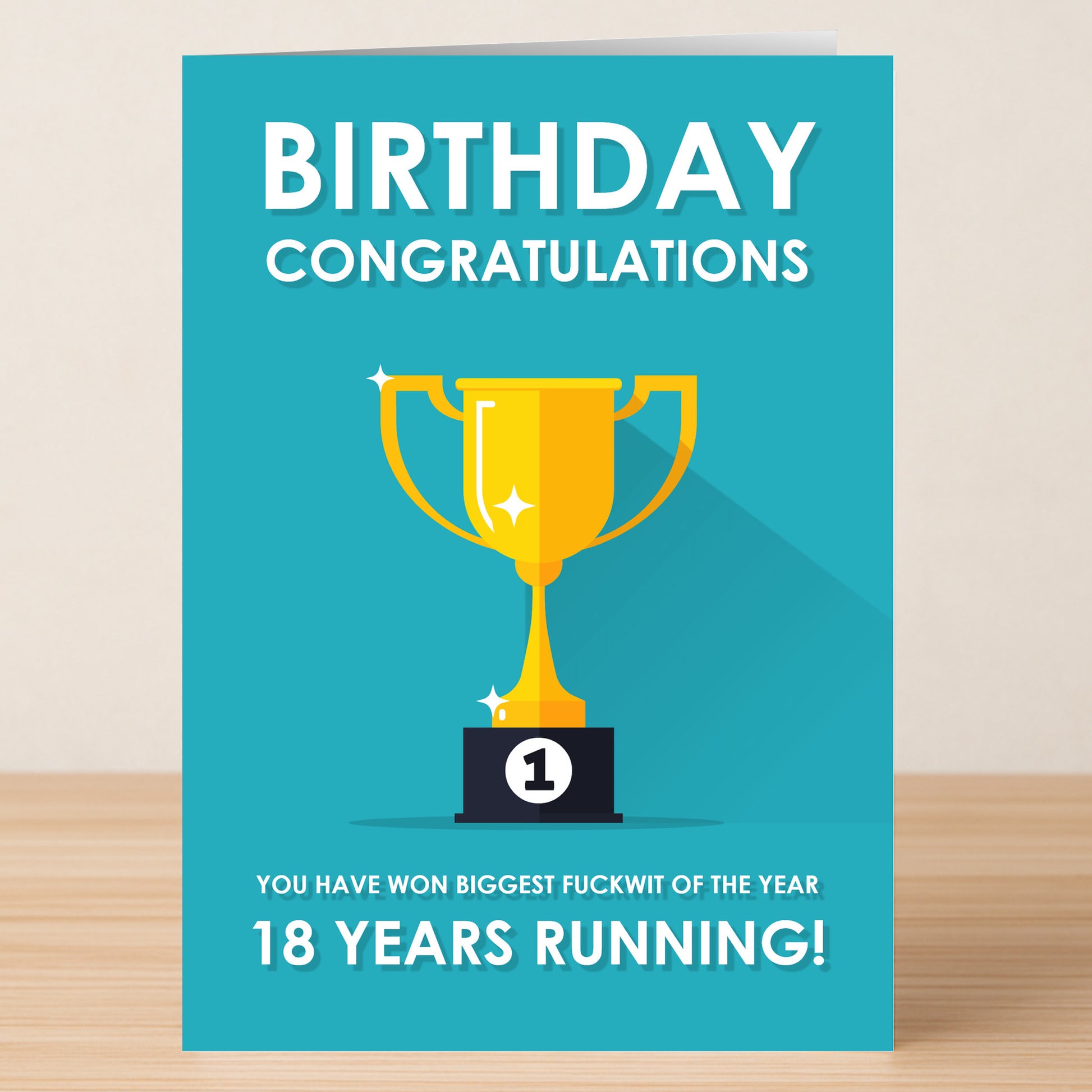 Celebrate an 18th birthday with the "18 - Running 18 Insulting Birthday Card" from Twisted Gifts, featuring a gold trophy and the message: “Birthday Congratulations. You have won biggest fuckwit of the year 18 years running!”.