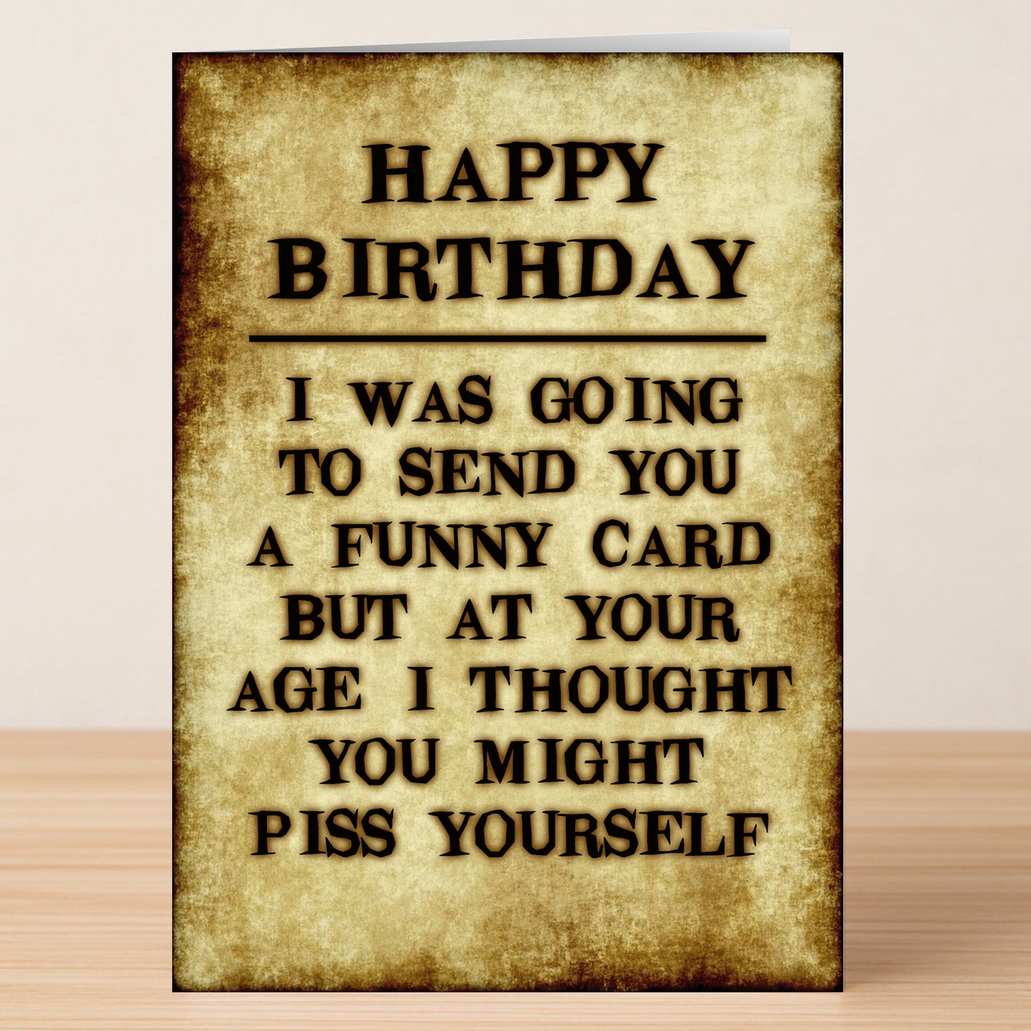 The Piss Yourself Insulting Birthday Card by Twisted Gifts features an aged paper look and reads: "HAPPY BIRTHDAY. I was going to send you a funny card but at your age I thought you might piss yourself." A hilarious birthday gift!.