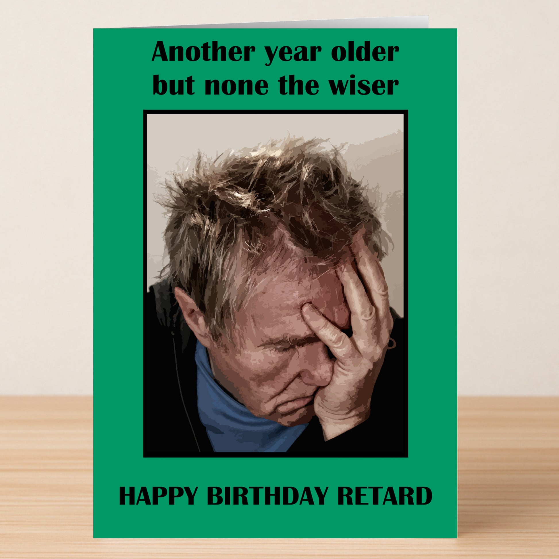 A man holding his head, reacting as if he just read the Non The Wiser Insulting Birthday Card by Twisted Gifts.