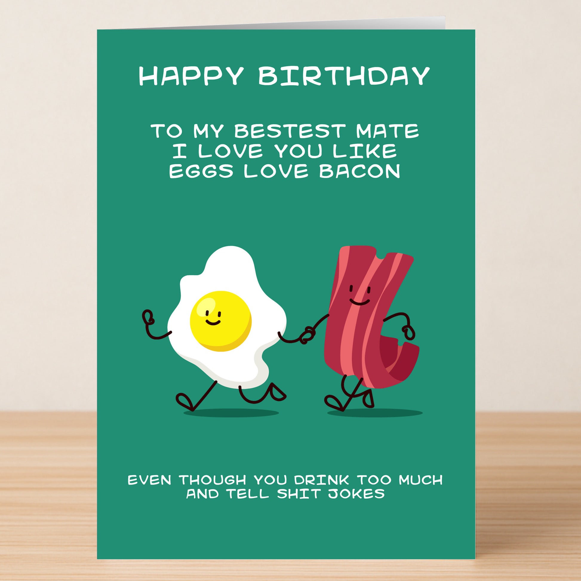 The Twisted Gifts Eggs & Bacon Funny Birthday Card features a smiling egg and bacon holding hands with playful text, perfect for celebrating friendship with humor and a bit of light-hearted teasing.