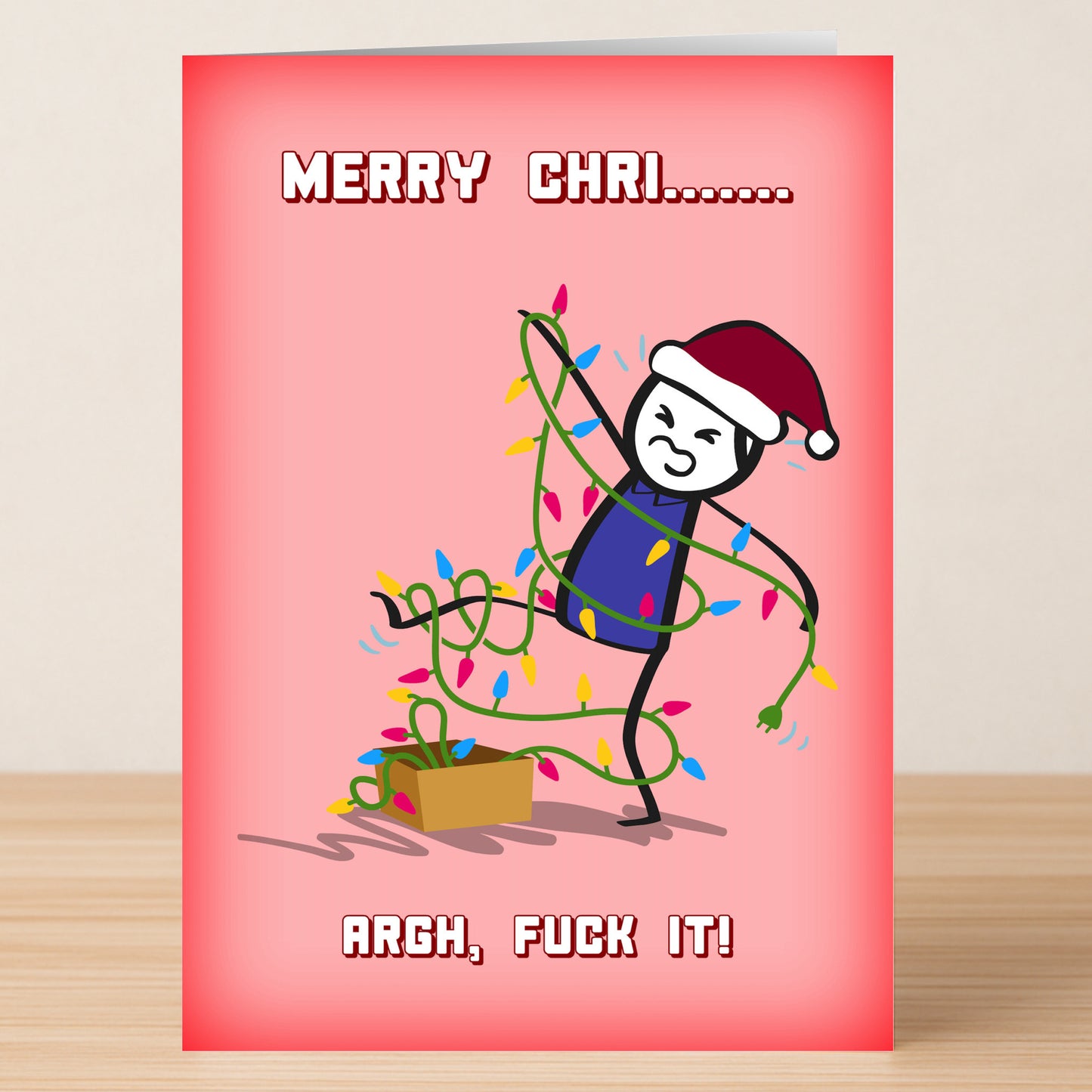 The ARGH Funny Christmas Card by Twisted Gifts features a stick figure in a Santa hat tangled in lights beside a box, with "MERRY CHRI........ ARGH, FUCK IT!" on a pink background—perfect for sending some holiday laughs.