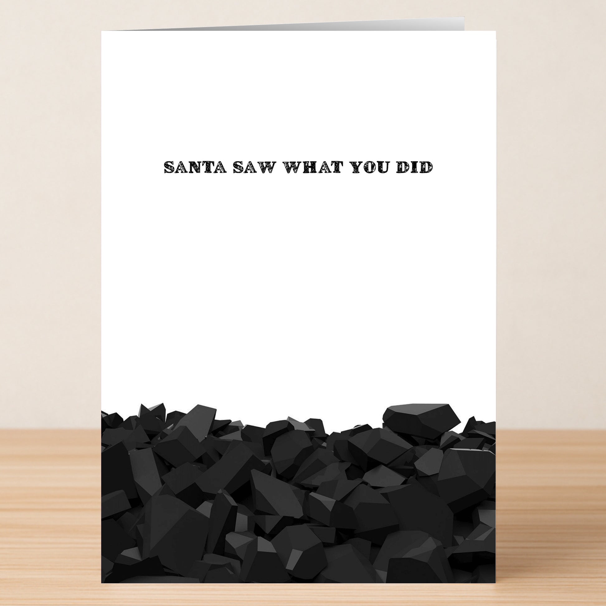 Twisted Gifts' Santa Saw Funny Christmas Card features the phrase "SANTA SAW WHAT YOU DID" above piles of black coal on a wooden surface—a playful way to spread holiday cheer to anyone who loves humor.