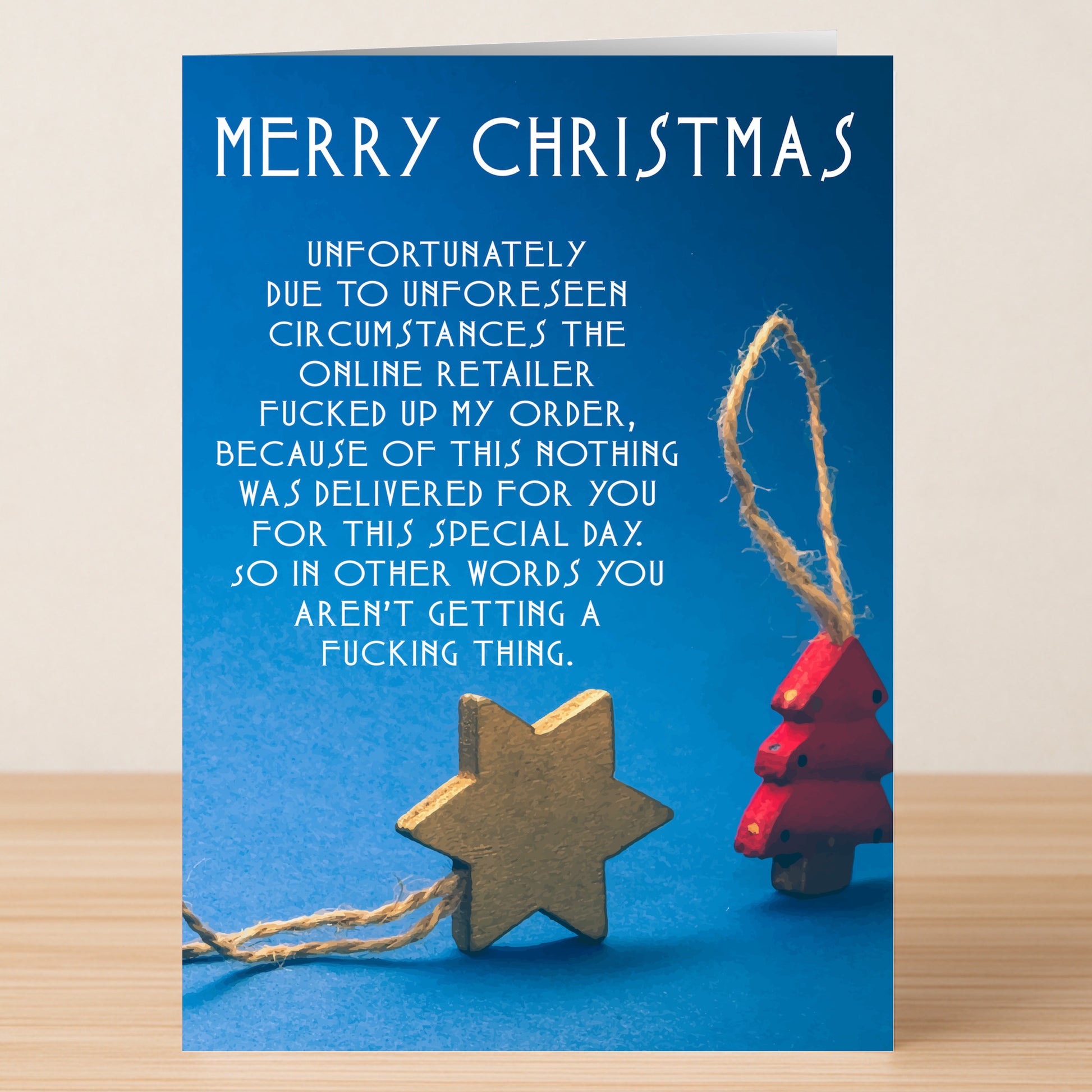 Spread holiday laughter with the Unfortunately Funny Christmas Card by Twisted Gifts, featuring a witty message about a lost gift due to retailer error, plus charming wooden star and tree decorations on string.