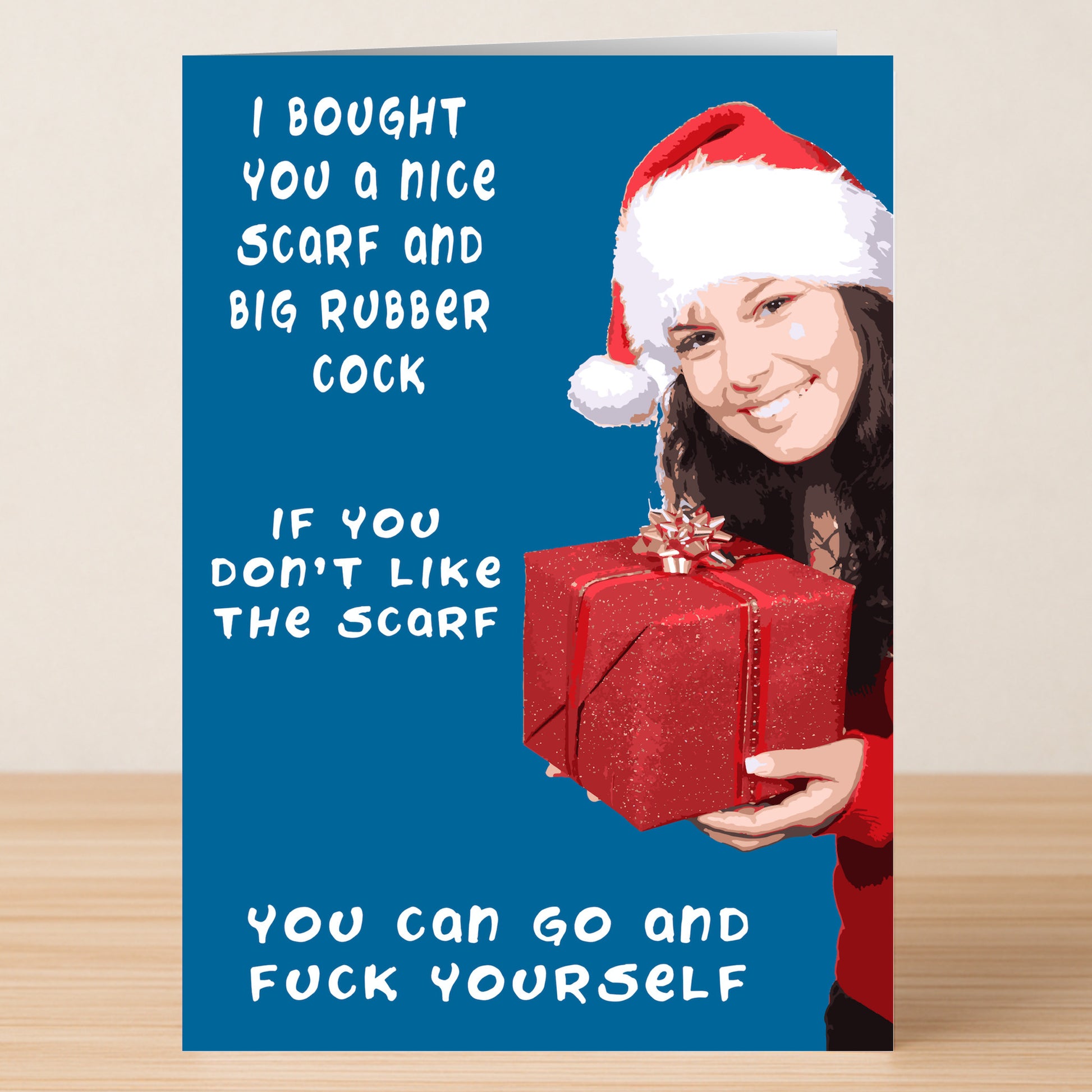 The Nice Scarf Rude Christmas Card by Twisted Gifts shows a woman in a Santa hat holding a red gift box, with the cheeky message: "I bought you a nice scarf and big rubber cock. If you don't like the scarf, you can go and fuck yourself.