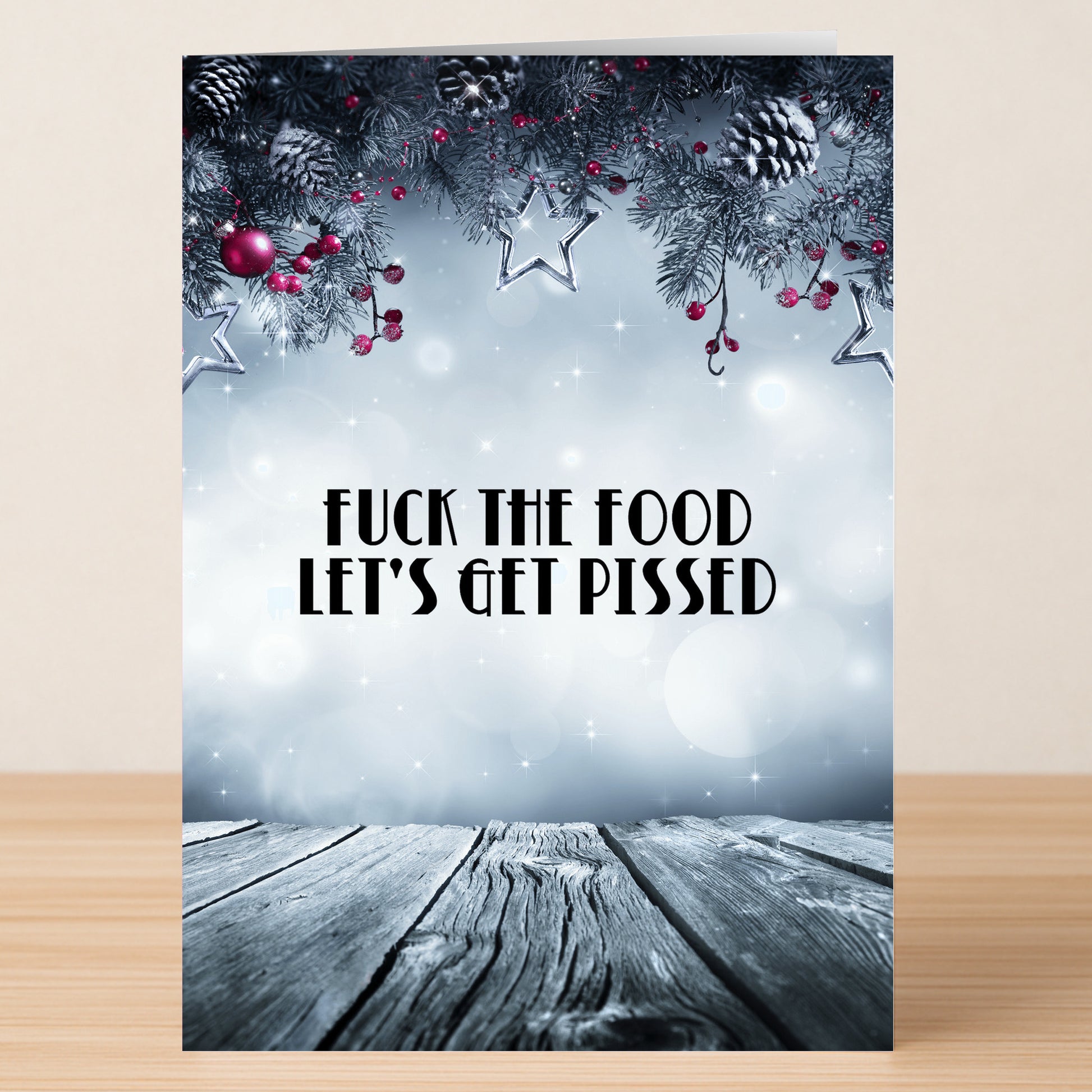 The Fuck The Food Funny Christmas Card by Twisted Gifts showcases pine branches, berries, and stars above the bold text "FUCK THE FOOD LET'S GET PISSED"—an ideal way to add humor to your holiday festivities.