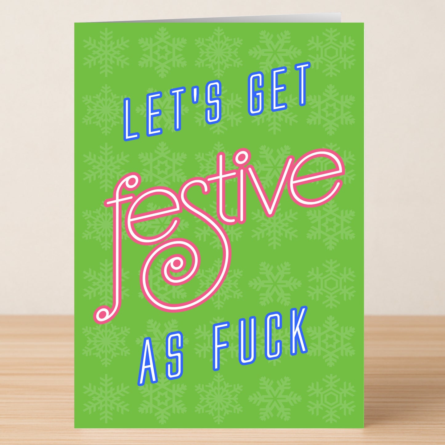 Twisted Gifts' Festive Funny Christmas Card features green snowflake patterns and bold "Let's get festive as fuck" text in blue and pink—a hilarious way to spread holiday cheer.