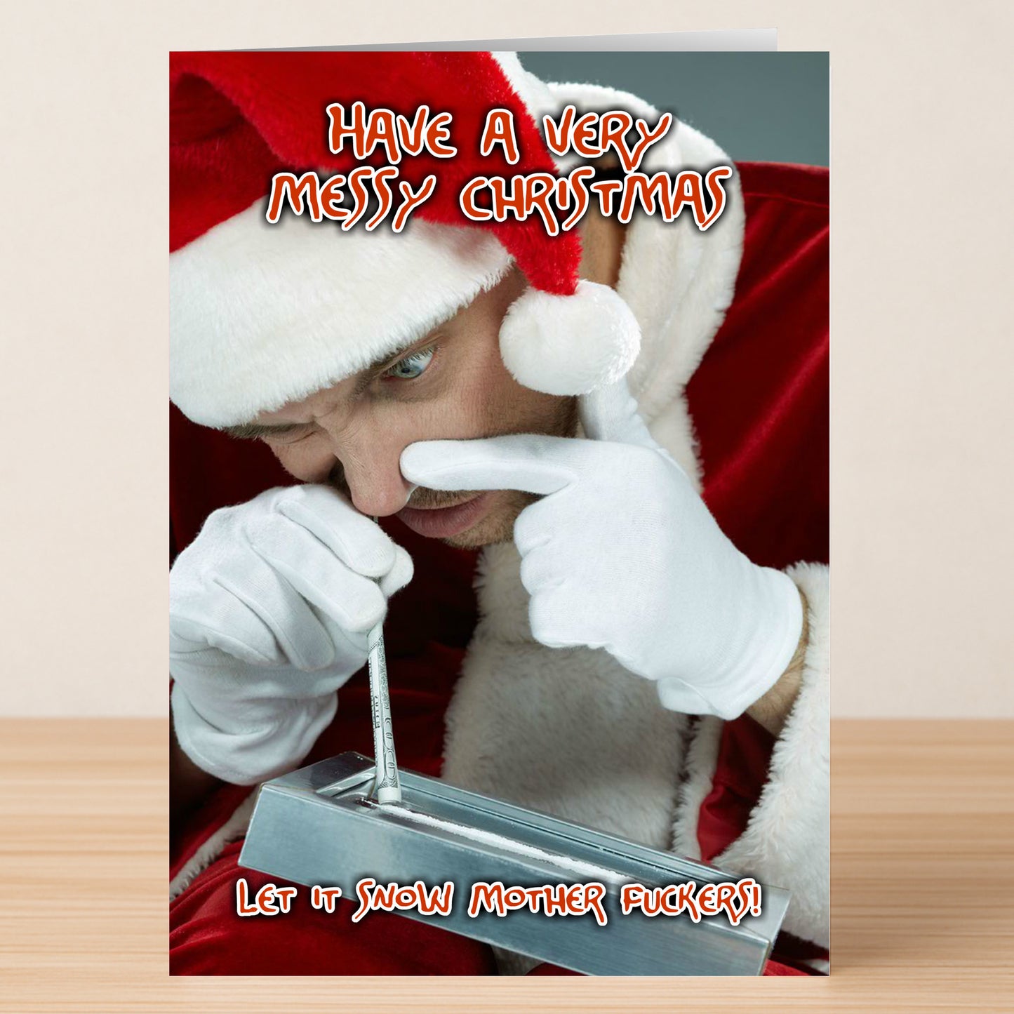 The Let It Snow Funny Christmas Card by Twisted Gifts shows Santa pretending to snort a white substance with a straw from a metal tray, with the text "Have a very messy Christmas. Let it snow mother fuckers!"—a hilarious holiday card.