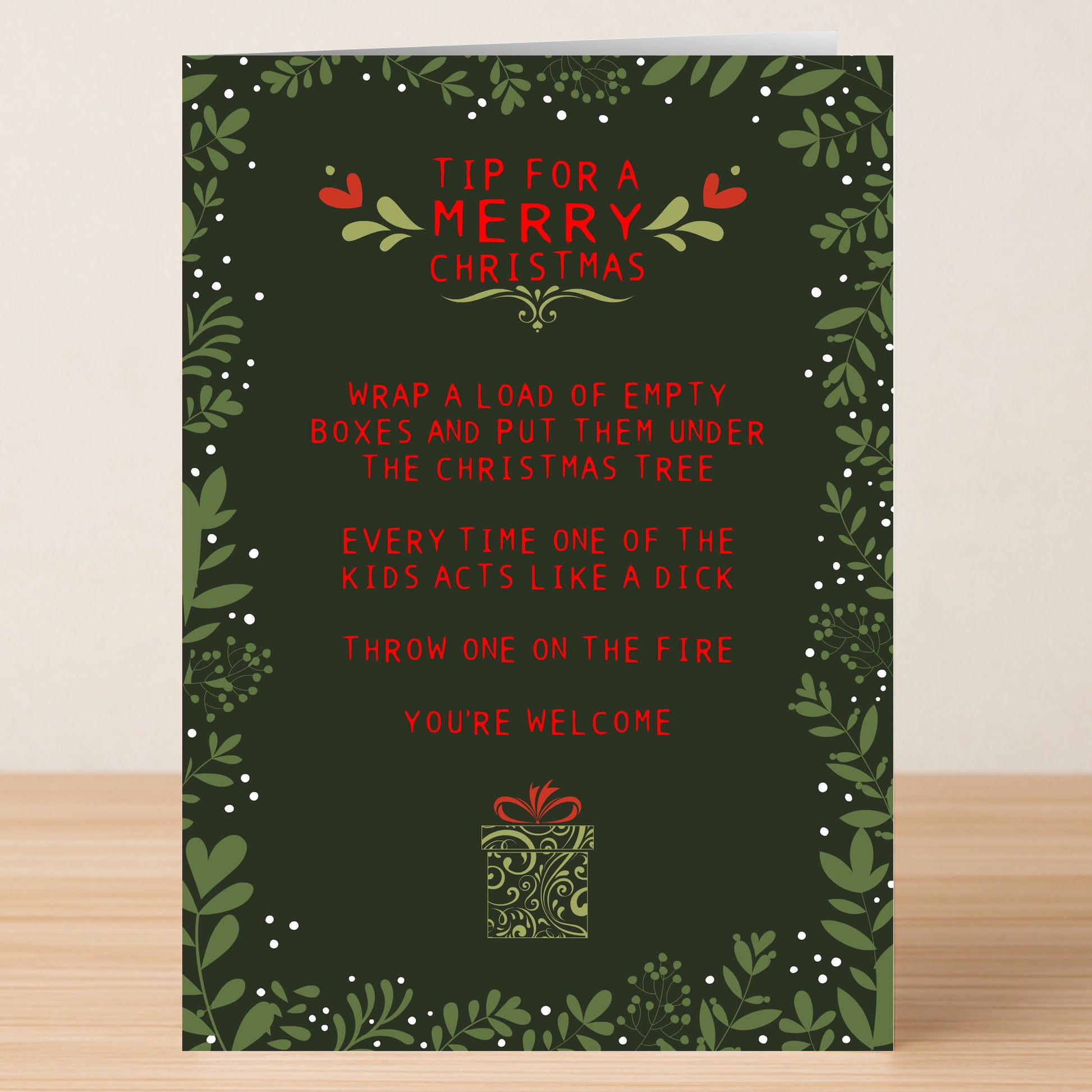Spread holiday laughs with the "Christmas Tip Funny Christmas Card" from Twisted Gifts, featuring festive green foliage and red text that jokes about wrapping empty boxes and tossing them in the fire to keep kids in line!.
