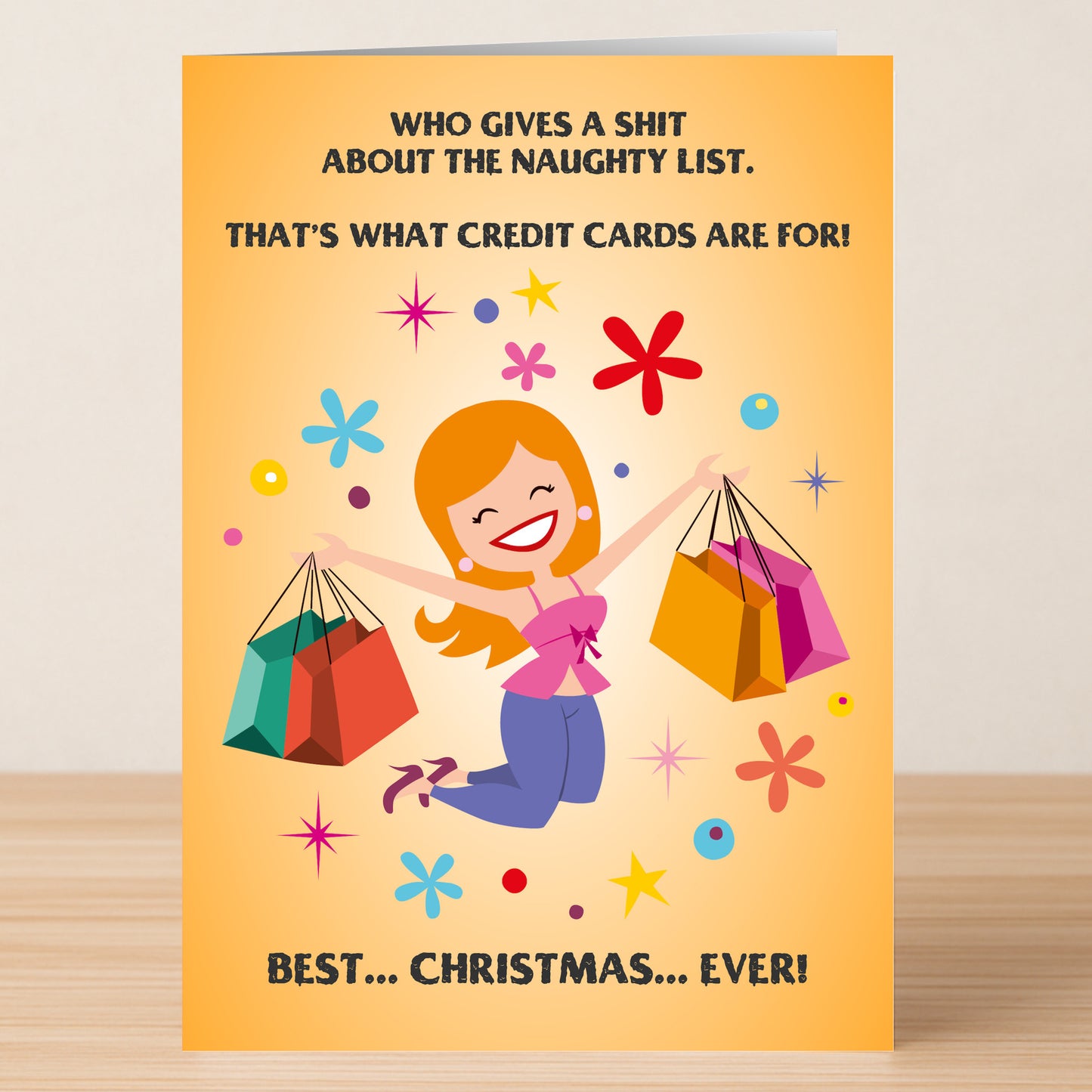 The Credit Funny Christmas Card by Twisted Gifts features a smiling woman jumping with shopping bags and a playful holiday message about skipping the naughty list and using credit cards for Christmas.