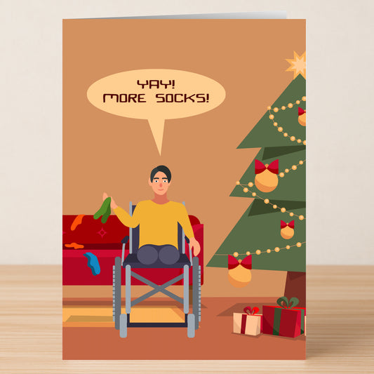 A person in a wheelchair joyfully holds socks by the Christmas tree—perfect for the Twisted Gifts "More Socks Funny Christmas Card" to spread holiday cheer!.