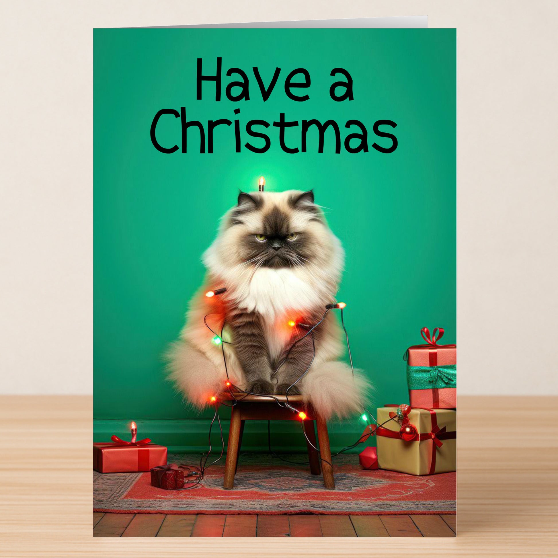 A long-haired cat sits on a chair wrapped in Christmas lights, surrounded by presents, under "Have a Meowy Christmas"—the perfect Have A Christmas Funny Christmas Card from Twisted Gifts.