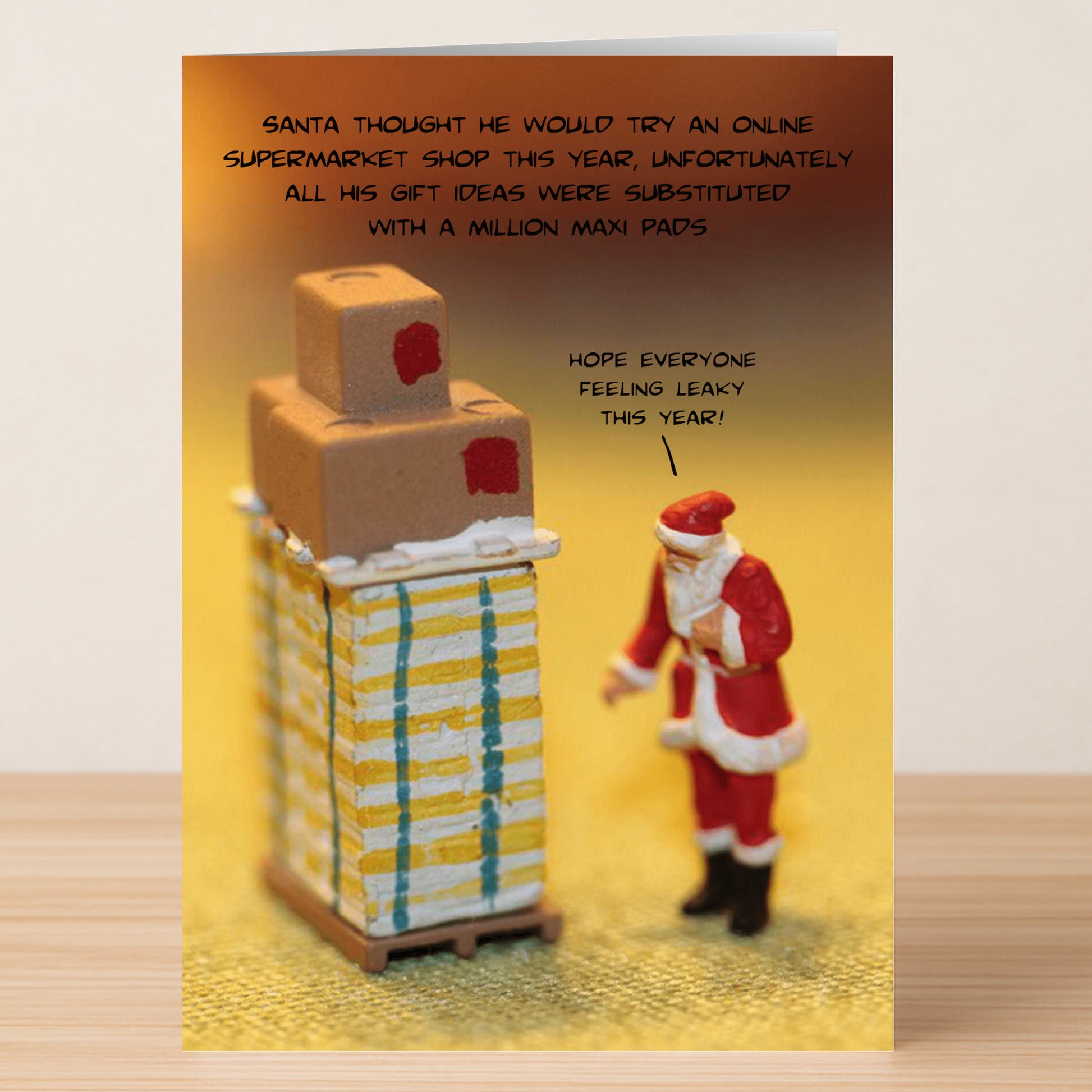 The Leaky Funny Christmas Card by Twisted Gifts shows Santa beside boxes labeled maxi pads, joking about online shopping mishaps—delivering laughs with a holiday twist!.