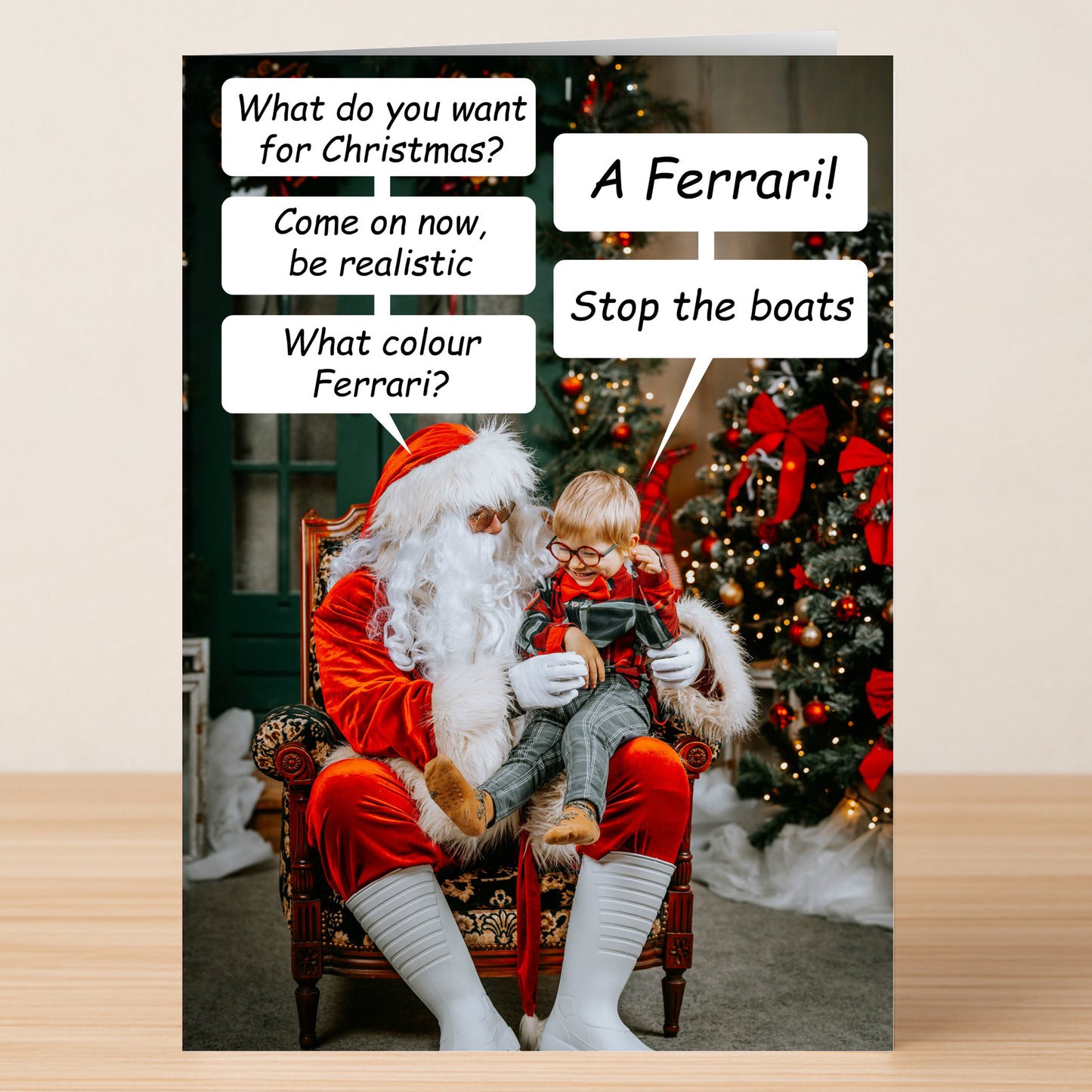 The Boats Funny Christmas Card by Twisted Gifts features Santa with a child on his lap, festive tree behind, and hilarious speech bubbles about wanting a Ferrari and "Stop the boats," making it a quirky, unique card full of holiday cheer.