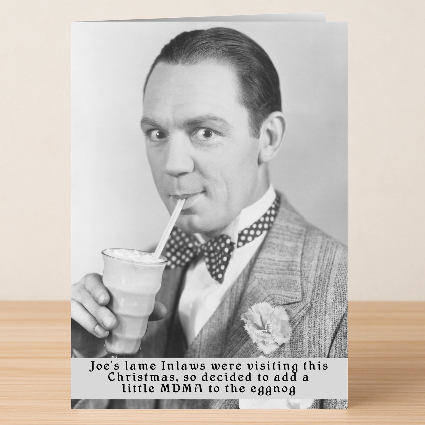 A man in a suit sips from a straw; beneath, playful text jokes about spiking eggnog with MDMA when in-laws visit. The Inlaws Funny Christmas Card by Twisted Gifts brings cheeky humor to your holiday greetings—perfect for a good laugh!.