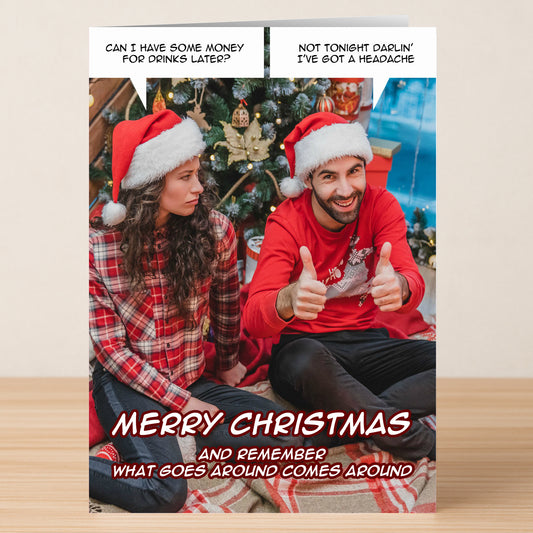 The What Goes Around Funny Christmas Card by Twisted Gifts features a man giving a thumbs up and an annoyed woman in Christmas attire by the tree, with witty holiday greetings and dialogue for a humorous touch of cheer.