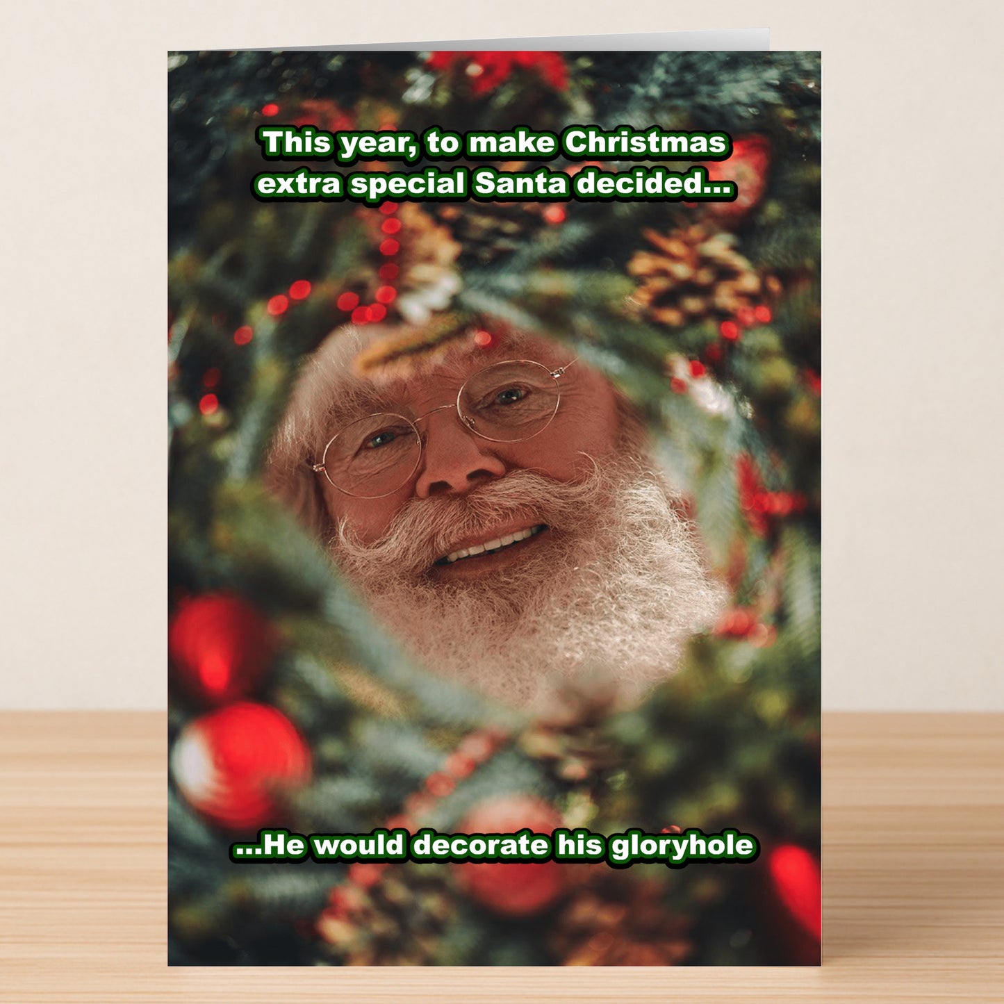 The Decorate Rude Christmas Card by Twisted Gifts features Santa smiling through a wreath's wild "gloryhole"—a cheeky, irreverent card perfect for adults who love an outrageous holiday laugh!.