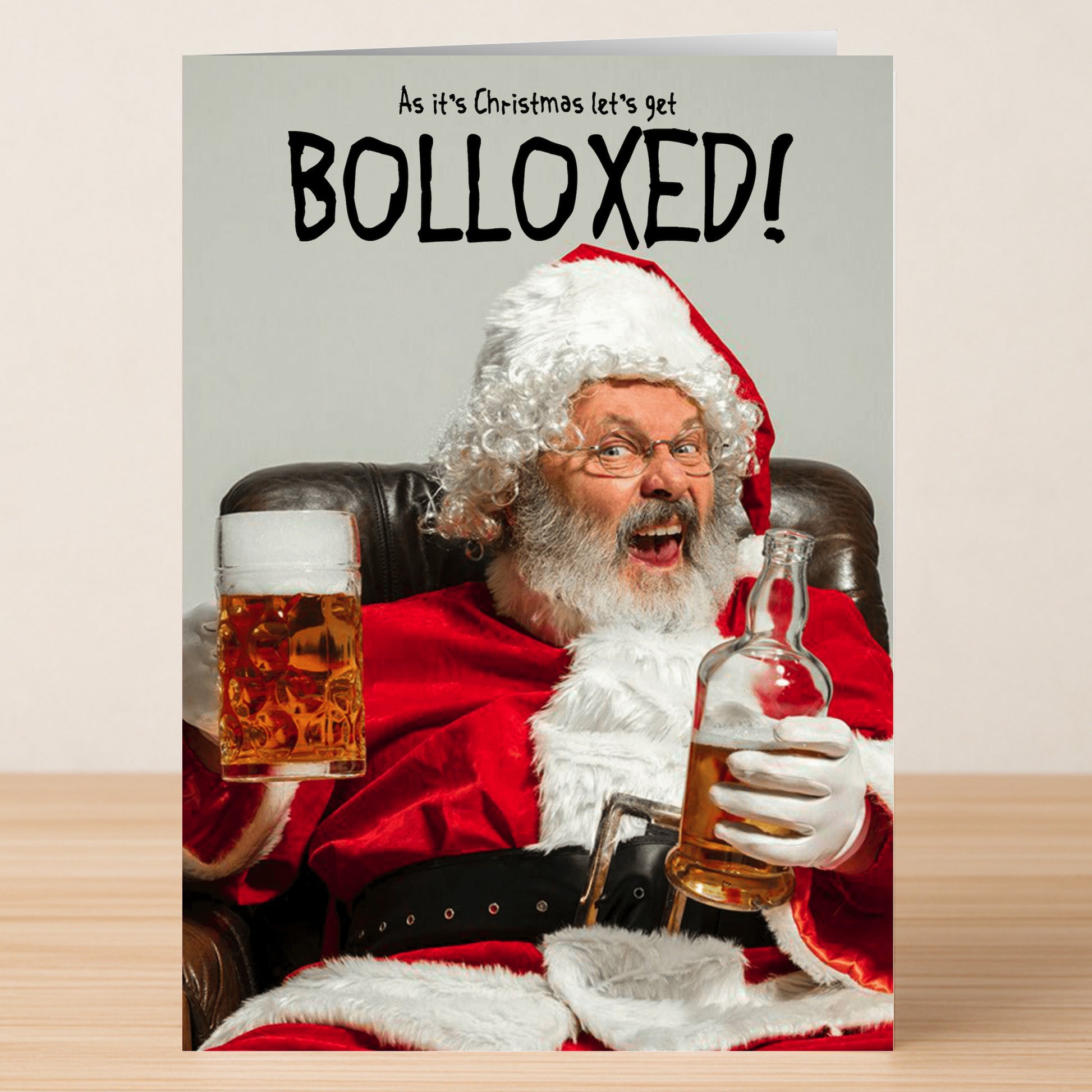 The Bolloxed Funny Christmas Card by Twisted Gifts features Santa on a chair with a beer mug and liquor bottle, captioned "As it's Christmas let's get BOLLOXED!"—perfect for spreading holiday cheer.