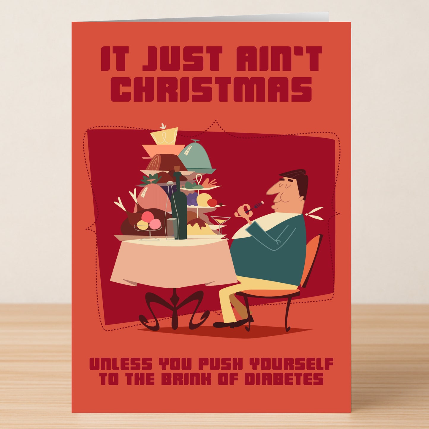 The Diabetes Funny Christmas Card by Twisted Gifts features a man feasting at a table with the text: “It just ain’t Christmas unless you push yourself to the brink of diabetes.” Bring holiday laughs with this hilarious card!.