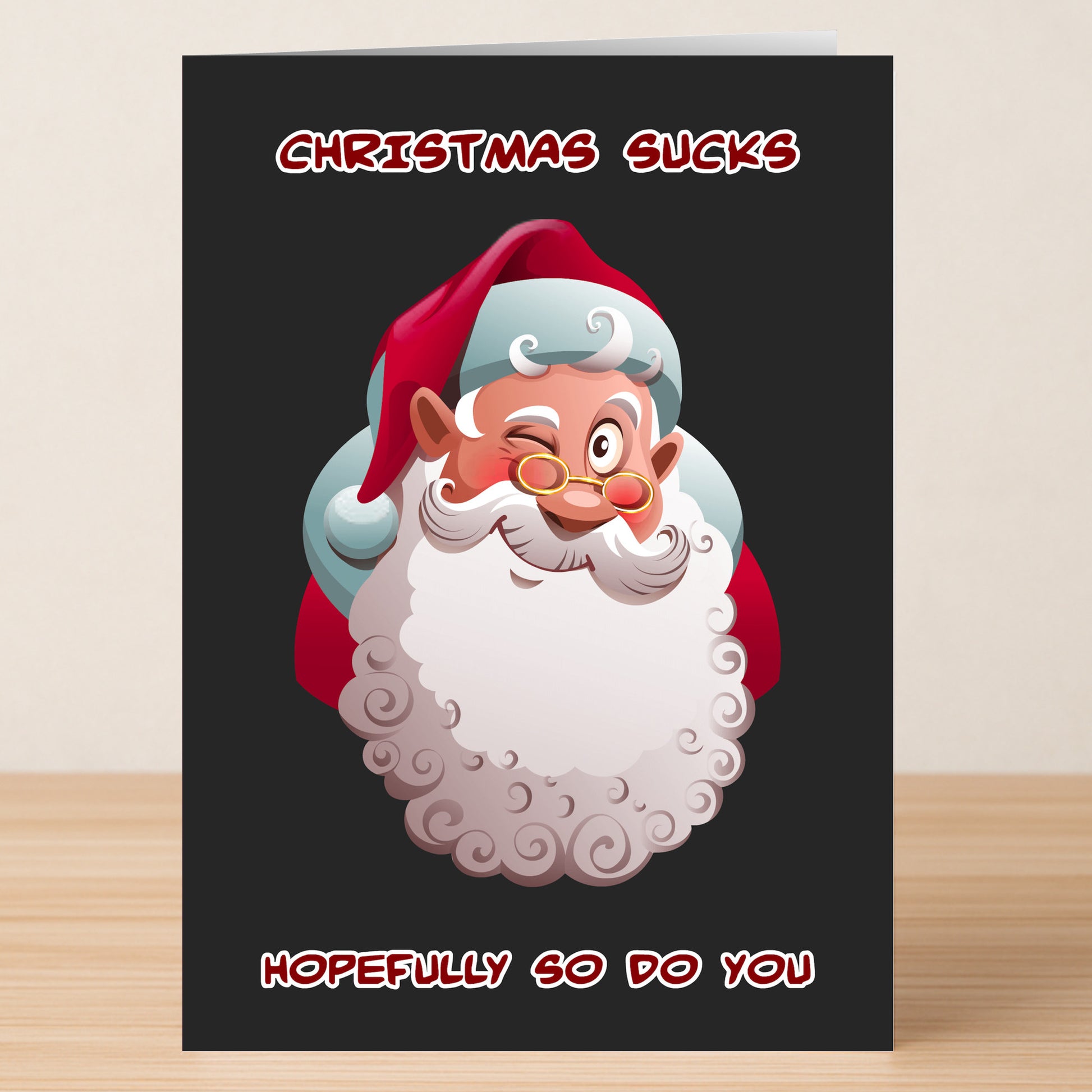 Twisted Gifts' "Xmas Sucks Funny Christmas Card" features a winking cartoon Santa, red text reading "CHRISTMAS SUCKS" above and "HOPEFULLY SO DO YOU" below, all on a black background—perfect for anyone with a cheeky sense of humor!.