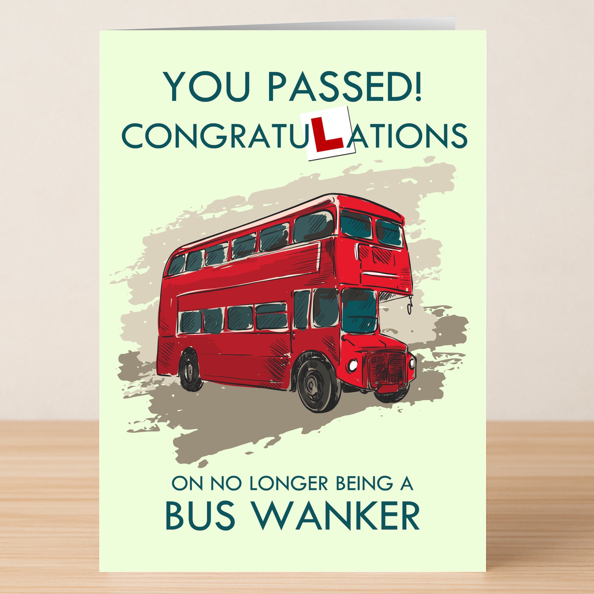 The Twisted Gifts Bus Wanker Insulting Congratulations Card humorously celebrates passing the driving test, featuring a red double-decker bus and the cheeky “bus wanker” joke.