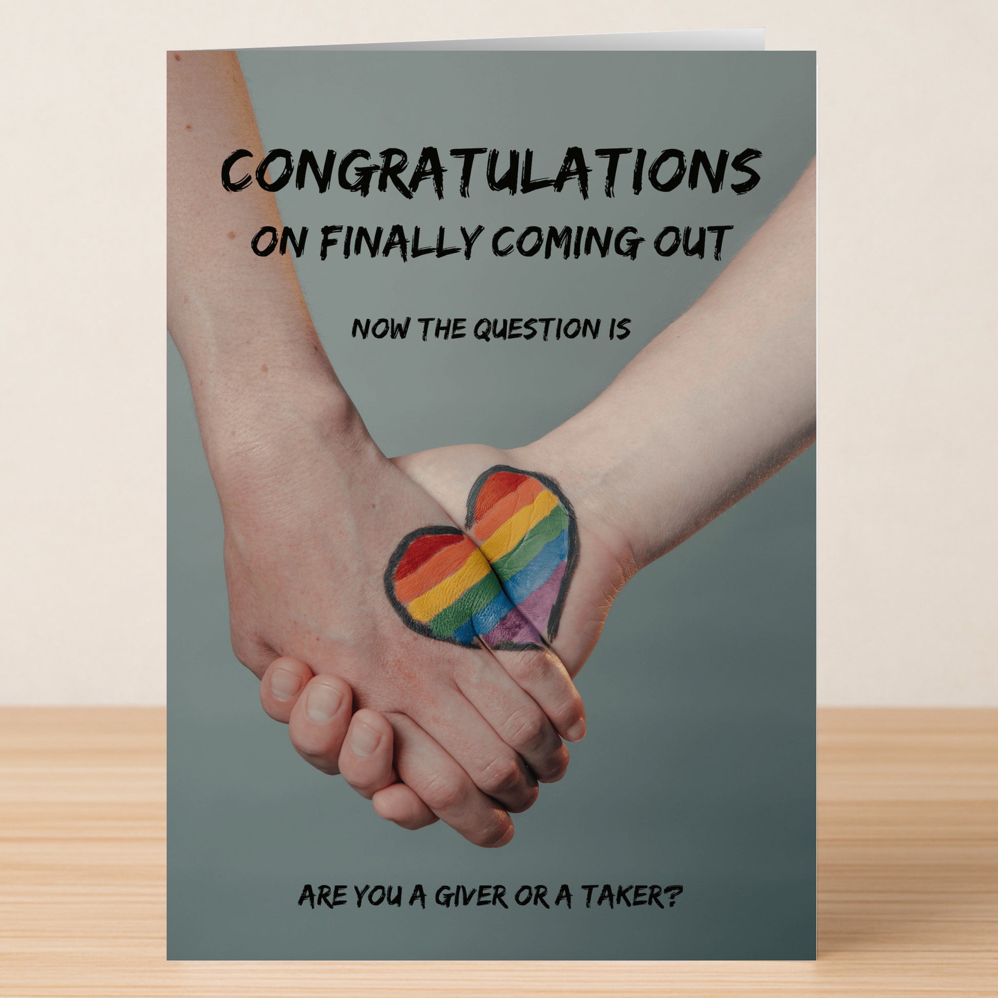 Two people hold hands with a rainbow heart painted across them. Text: "Congrats on coming out! Now the real question—are you a giver or taker?" Ideal for the Giver Or Taker Rude Congratulations Card by Twisted Gifts.