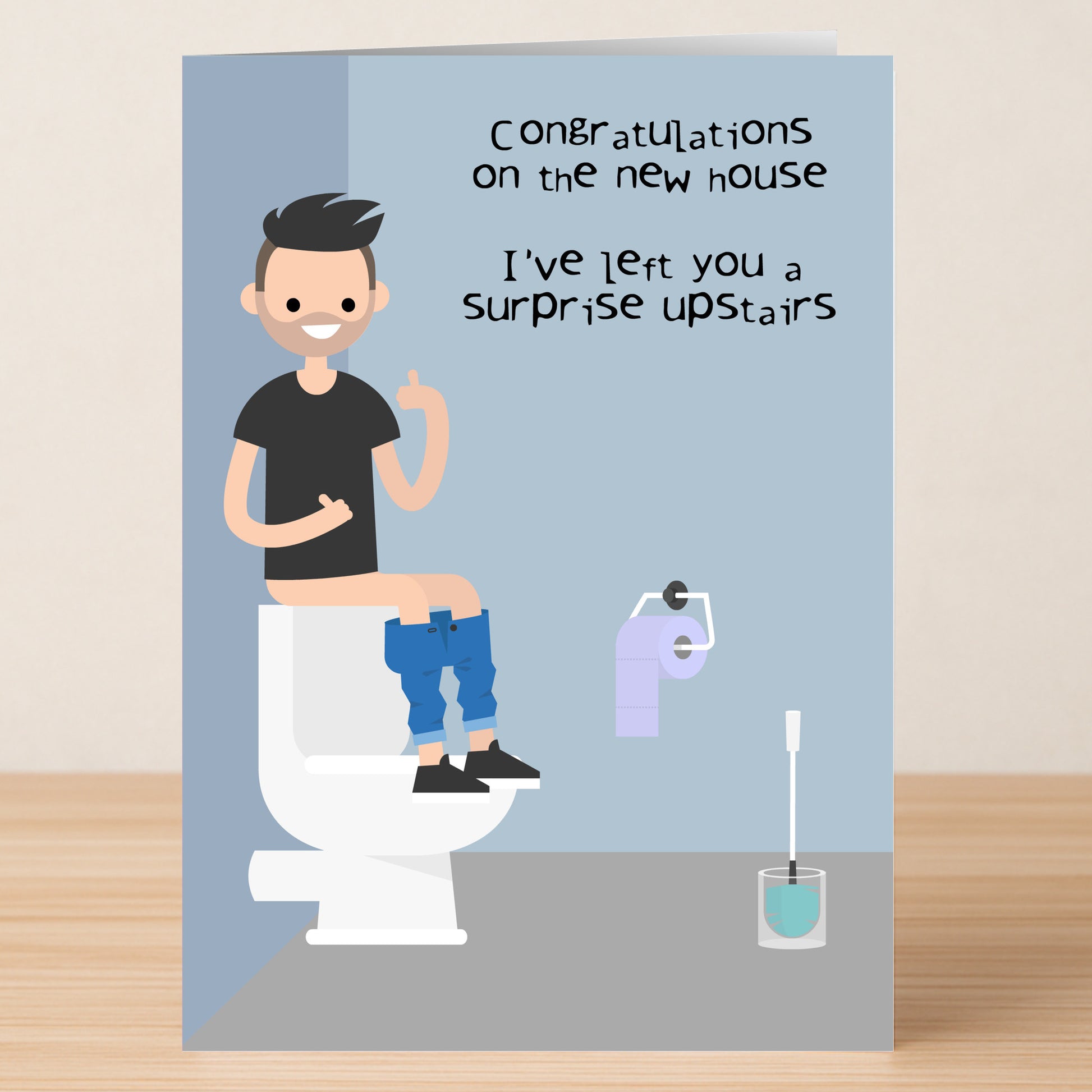 The Twisted Gifts Upper Decker Funny Congratulations Card features a cartoon on a toilet with the message: "Congratulations on the new house. I’ve left you a surprise upstairs.