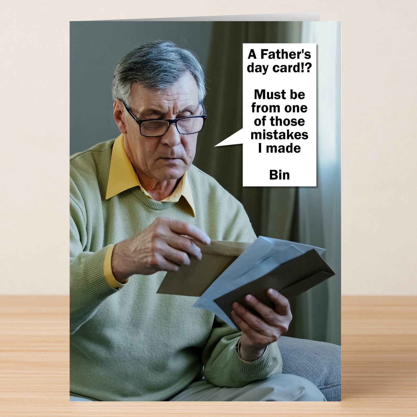 An older man in glasses and a yellow sweater opens an envelope. A speech bubble says, "A Father's Day card!? Must be from one of those mistakes I made." Bin Funny Father’s Day Card by Twisted Gifts.