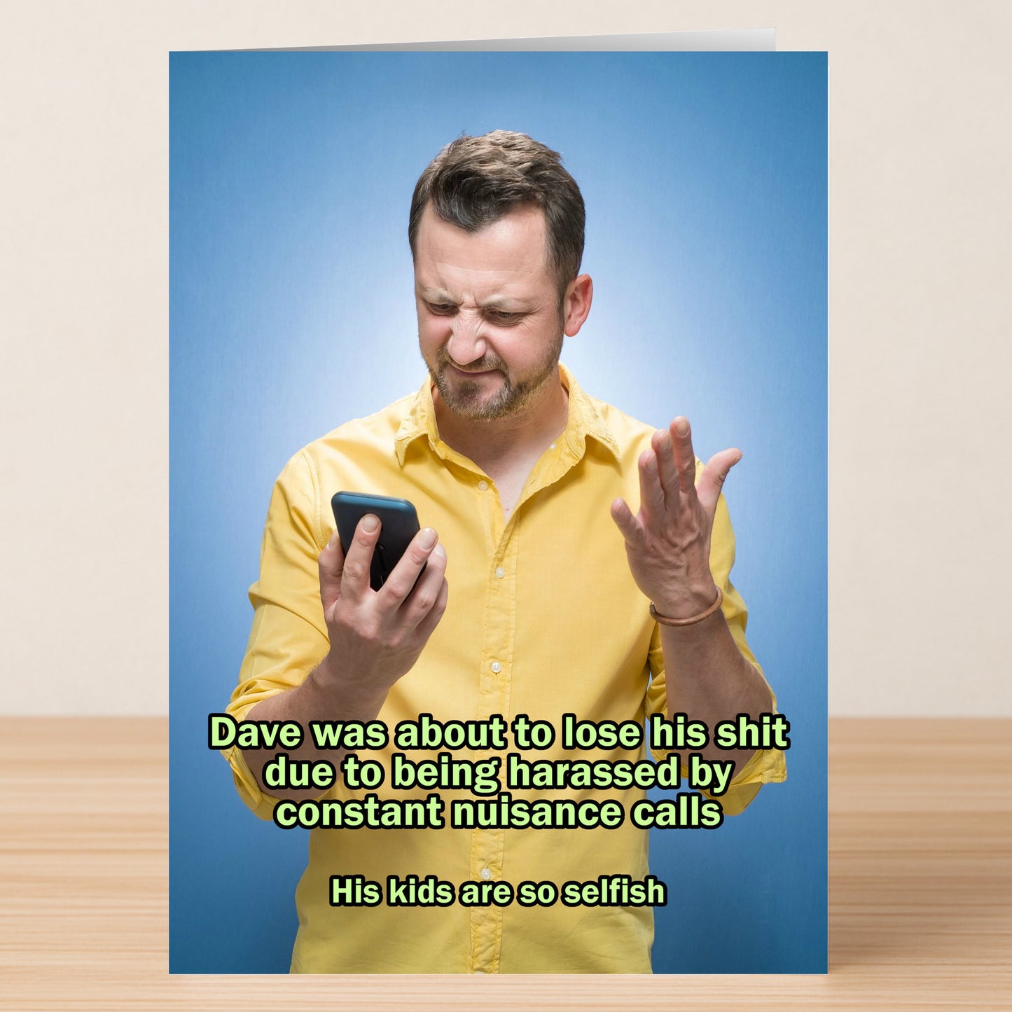 A man in a yellow shirt looks frustrated at his phone, raising one hand; Twisted Gifts’ Selfish Kids Funny Fathers Day Card jokes about getting nuisance calls from selfish kids.