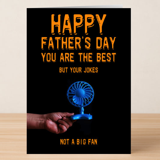 Celebrate Father’s Day with the Dad Jokes Funny Father's Day Card by Twisted Gifts, featuring orange text, a blue fan in hand, and playful humor: "Happy Father's Day. You are the best, but your jokes? Not a big fan.