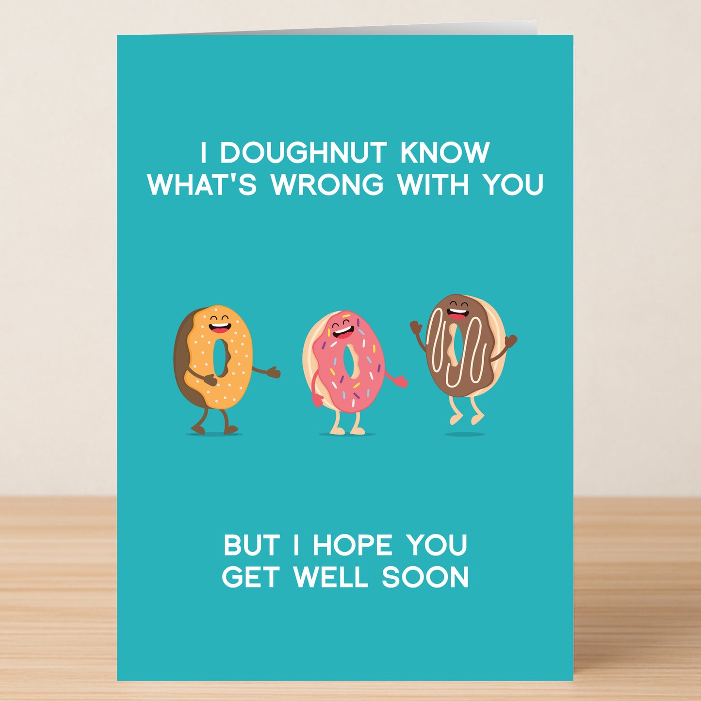 The Doughnut – Funny Get Well Soon Card by Twisted Gifts features cartoon donuts and the message "I doughnut know what's wrong with you but I hope you get well soon" on a teal background.