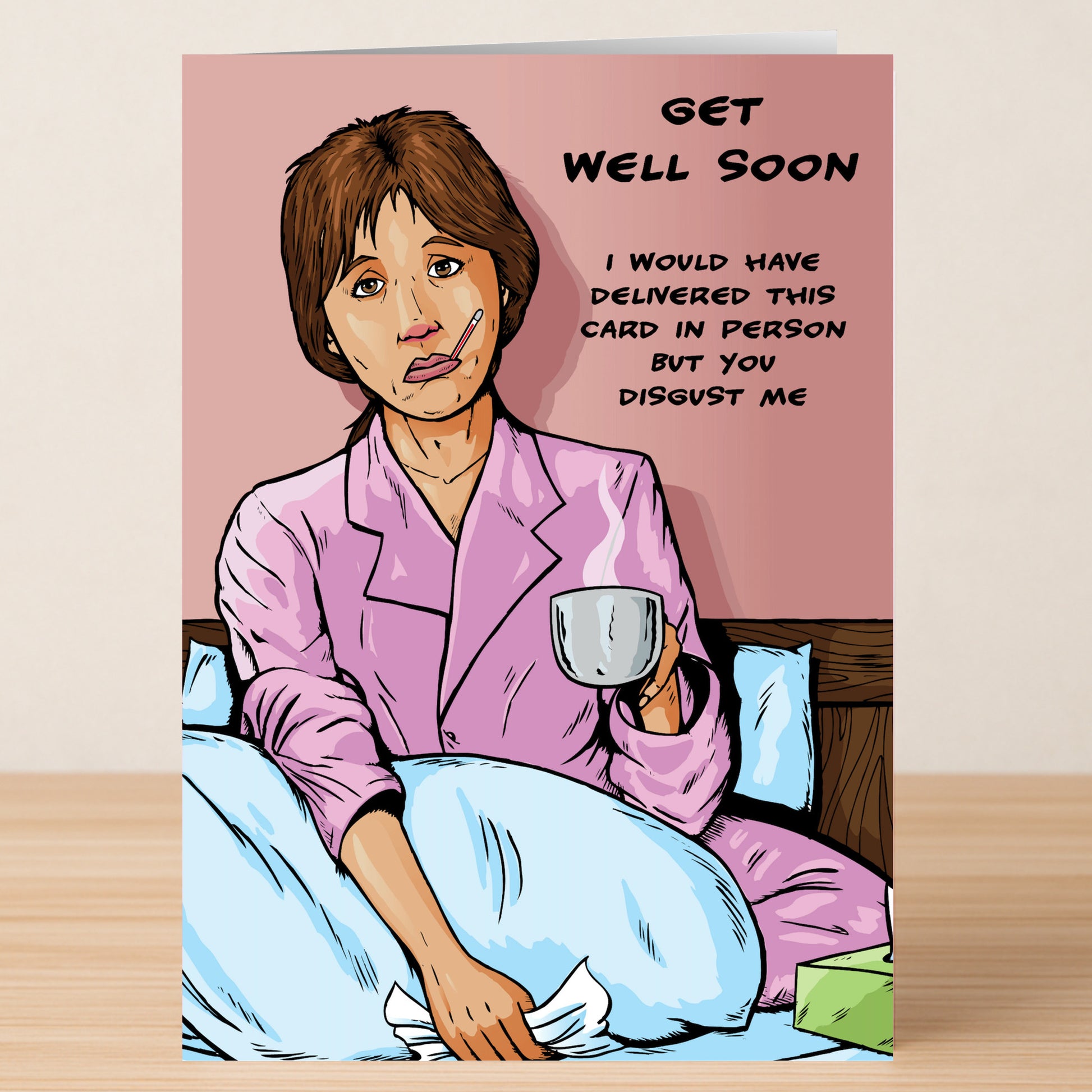 The Disgust Me Rude Get Well Soon Card by Twisted Gifts features a sick woman in bed with a mug and tissues. The card reads: "Get well soon. I would have delivered this in person but you disgust me." Perfect for sending cheeky wishes from afar.