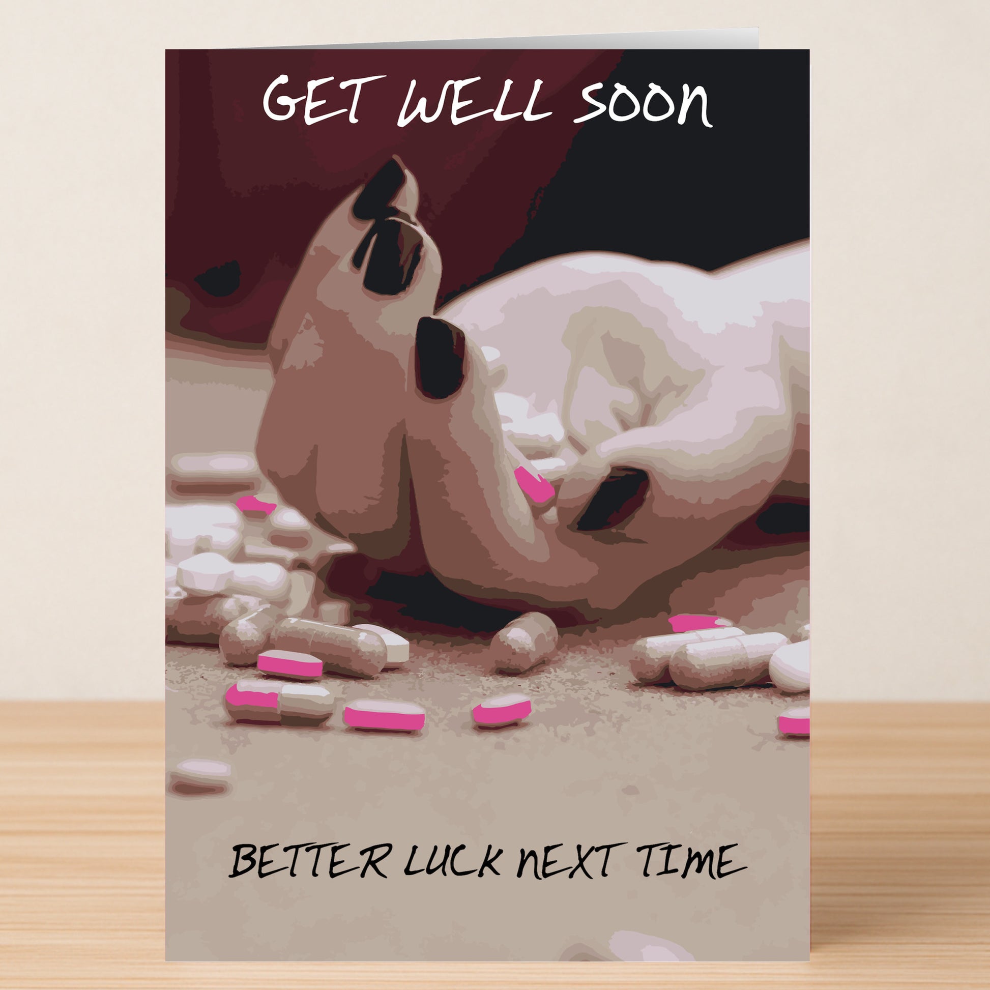 A hand on a table with scattered pills, like a darkly funny card from Twisted Gifts: "GET WELL SOON" at the top and "BETTER LUCK NEXT TIME" at the bottom—the Better Luck Next Time Rude Get Well Soon Card.