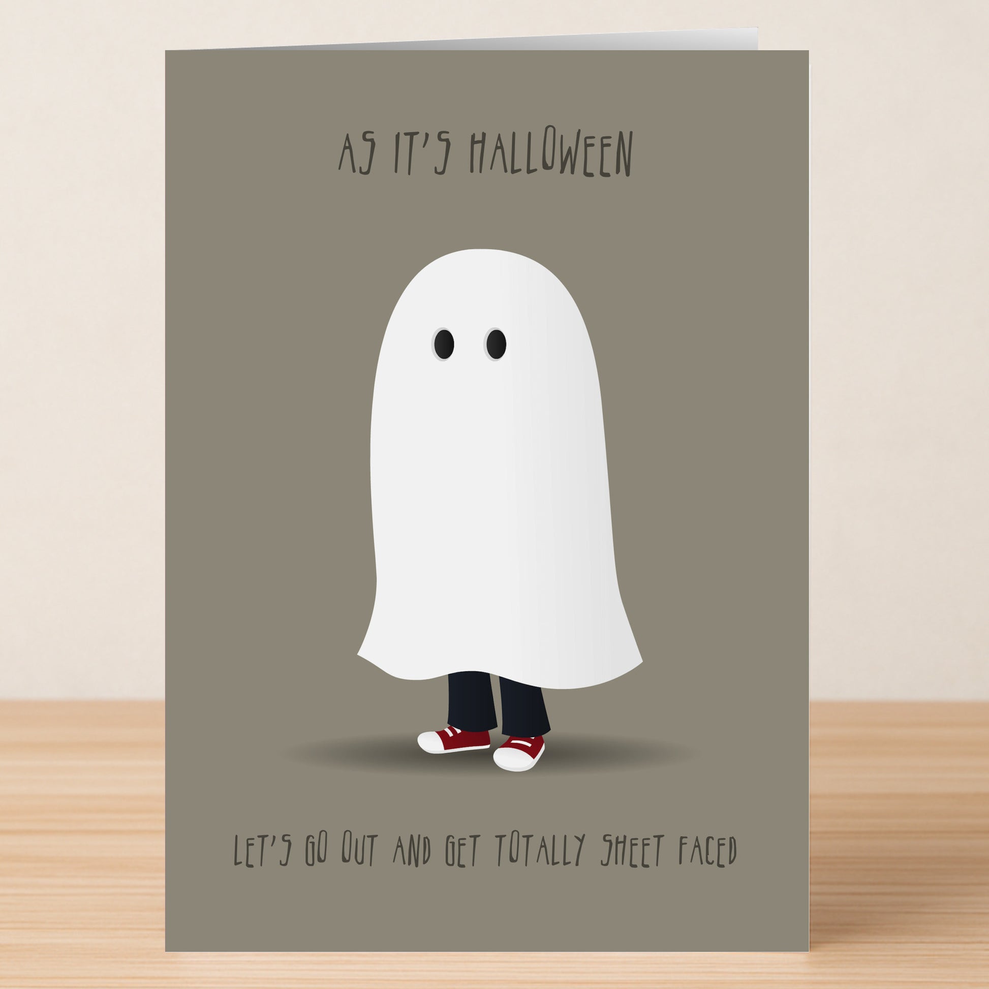 The Sheet Faced Funny Halloween Card by Twisted Gifts features a person in a ghost costume with red sneakers and the text "AS IT'S HALLOWEEN LET'S GO OUT AND GET TOTALLY SHEET FACED." A witty choice to send laughs!.
