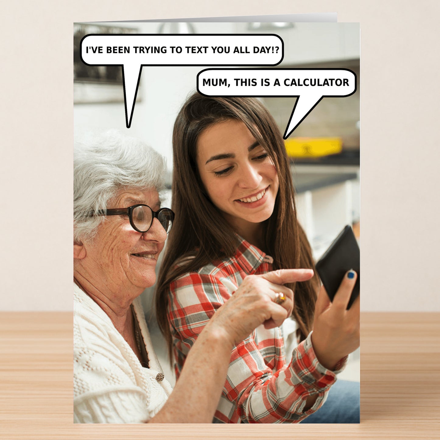 An elderly woman and a young woman smile together, looking at a device. Speech bubbles: "I’ve been trying to text you all day!?" and "Mum, this is a calculator." Calculator Funny Mother's Day Card by Twisted Gifts.