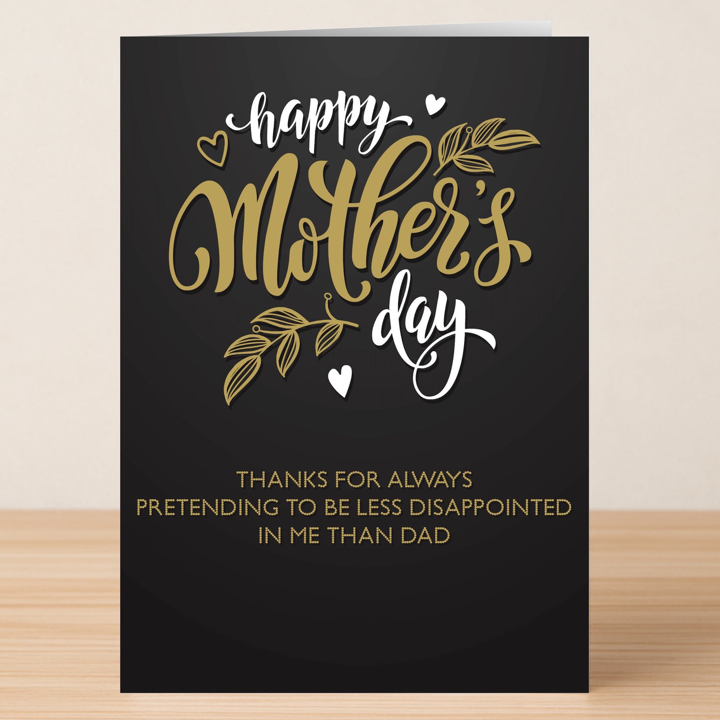 The Less Disappointed Funny Mother's Day Card by Twisted Gifts features gold and white text: "Happy Mother’s Day. Thanks for always pretending to be less disappointed in me than Dad.
