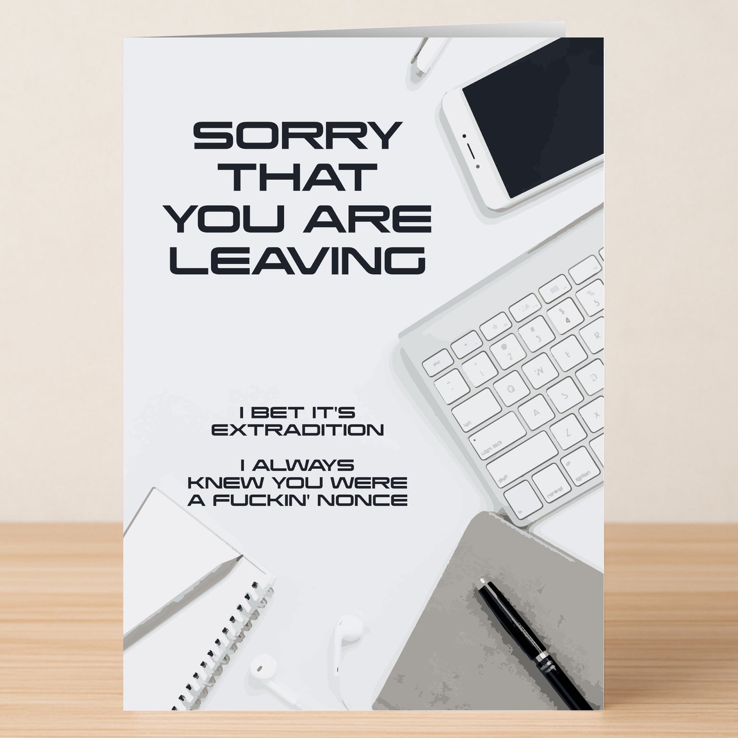 The Twisted Gifts Nonce Insulting Sorry Card sits on a desk among office items, featuring the message: "SORRY THAT YOU ARE LEAVING. I BET IT'S EXTRADITION. I ALWAYS KNEW YOU WERE A FUCKIN' NONCE.