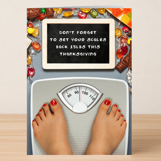 The Set Your Scales Insulting Thanksgiving Card by Twisted Gifts features someone on a bathroom scale amid candy holding a sign: "Don't forget to set your scales back 15 lbs this Thanksgiving." A clever, sarcastic holiday card.