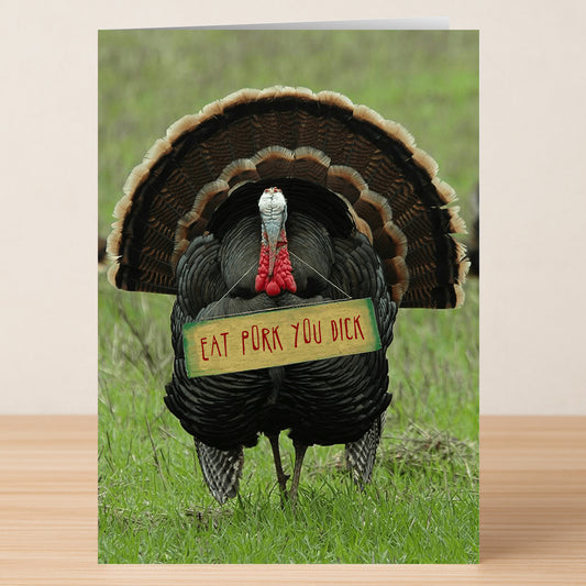 The Eat Pork Insulting Thanksgiving Card by Twisted Gifts features a turkey on grass with a sign that says, "EAT PORK YOU DICK”—perfect for anyone who enjoys funny and irreverent holiday cards.