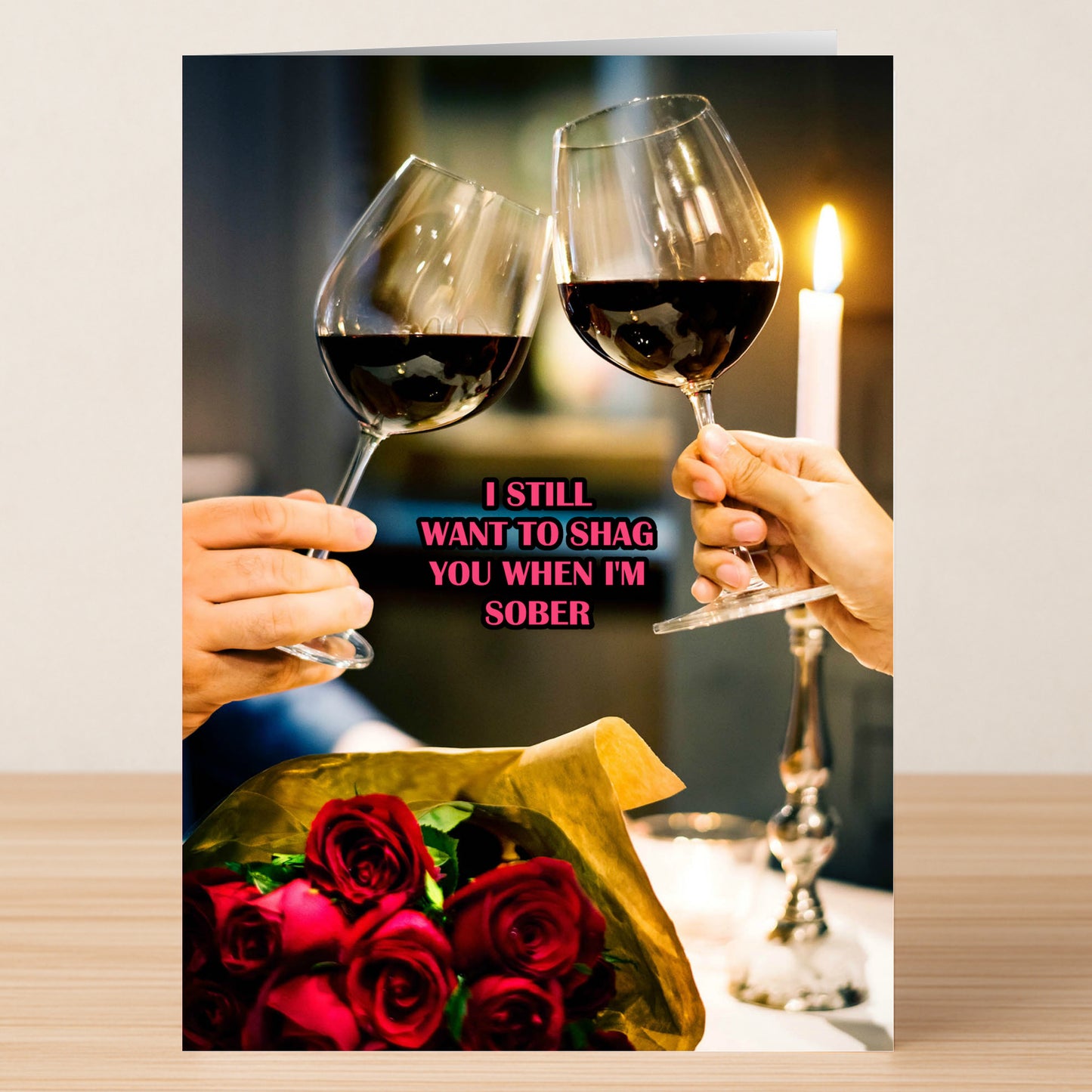 Two hands clink red wine glasses amid candlelight and roses, with "I STILL WANT TO SHAG YOU WHEN I'M SOBER" in pink—Twisted Gifts' Sober Insulting Valentine's Card, the perfect cheeky card for Valentine’s Day.