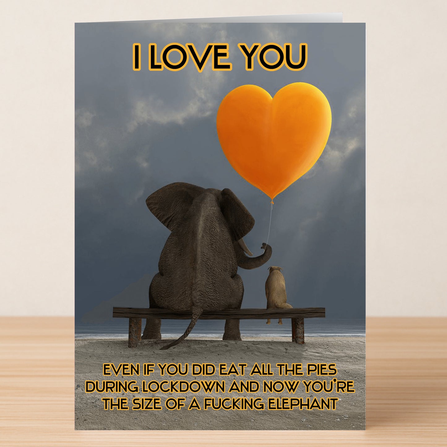 The Twisted Gifts "All The Pies" Funny Valentine's Card features an elephant and a smaller animal on a bench with a heart balloon, humorously celebrating love despite any lockdown weight gain.