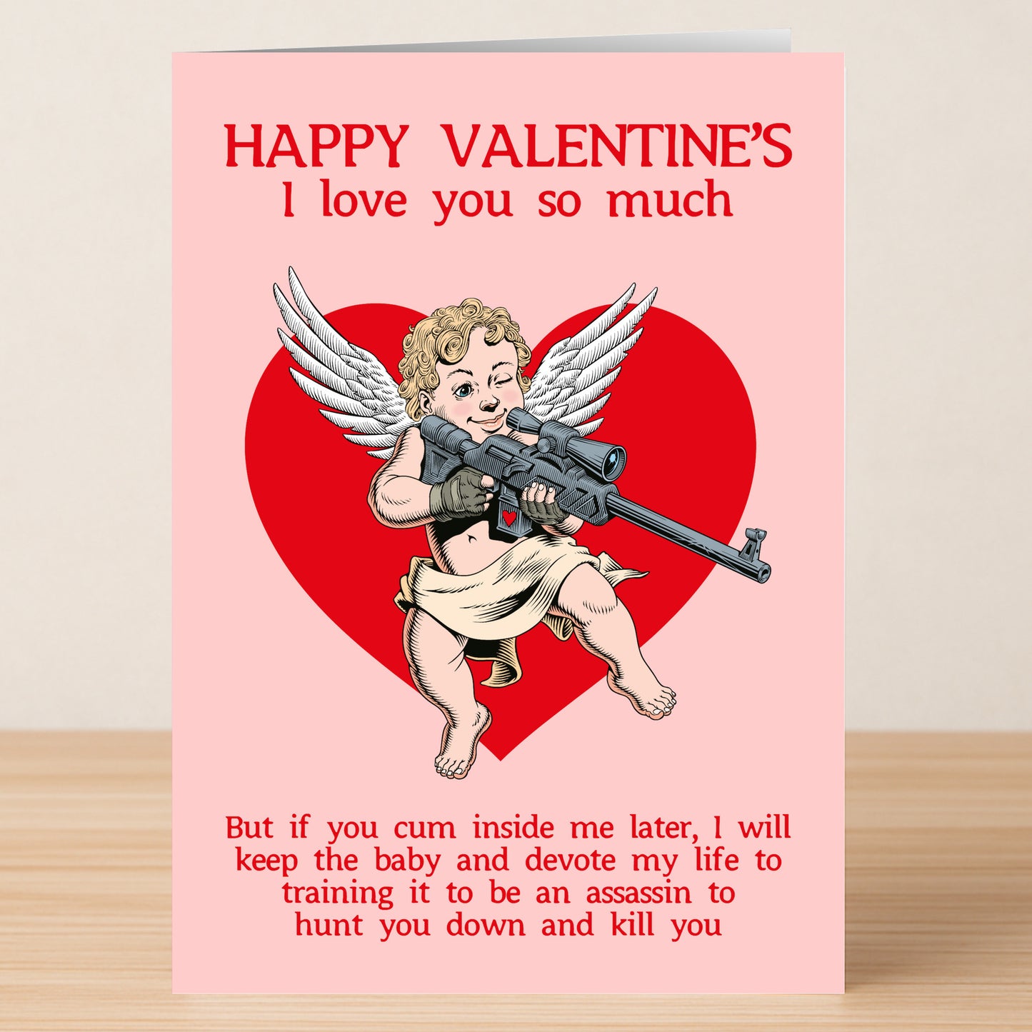 The Assassin Funny Valentine's Card by Twisted Gifts features a winged cherub with a sniper rifle in front of a red heart and witty, slightly threatening text—perfect for anyone with a playful sense of humor this Valentine’s Day.