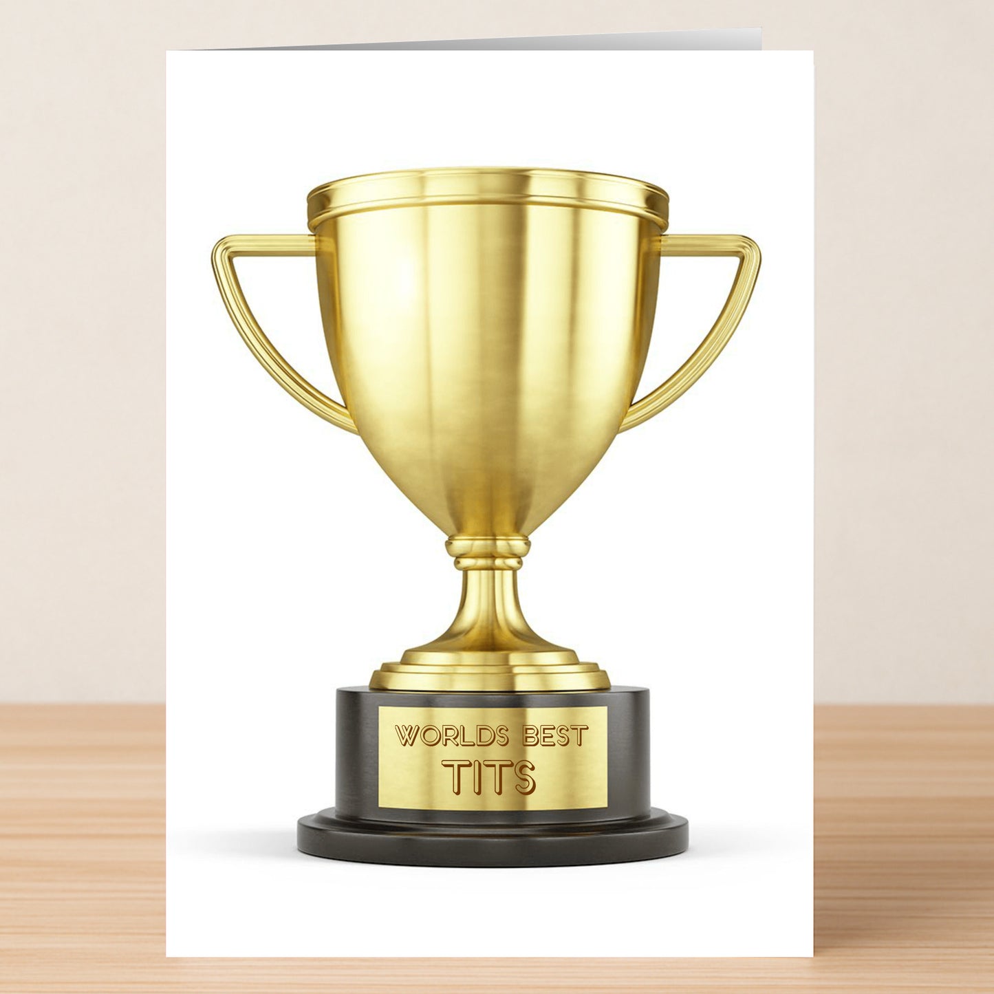 The Worlds Best Funny Valentine’s Card by Twisted Gifts features a gold trophy engraved with "WORLD'S BEST TITS," set against a plain background—ideal for sharing humor and love this Valentine's Day.