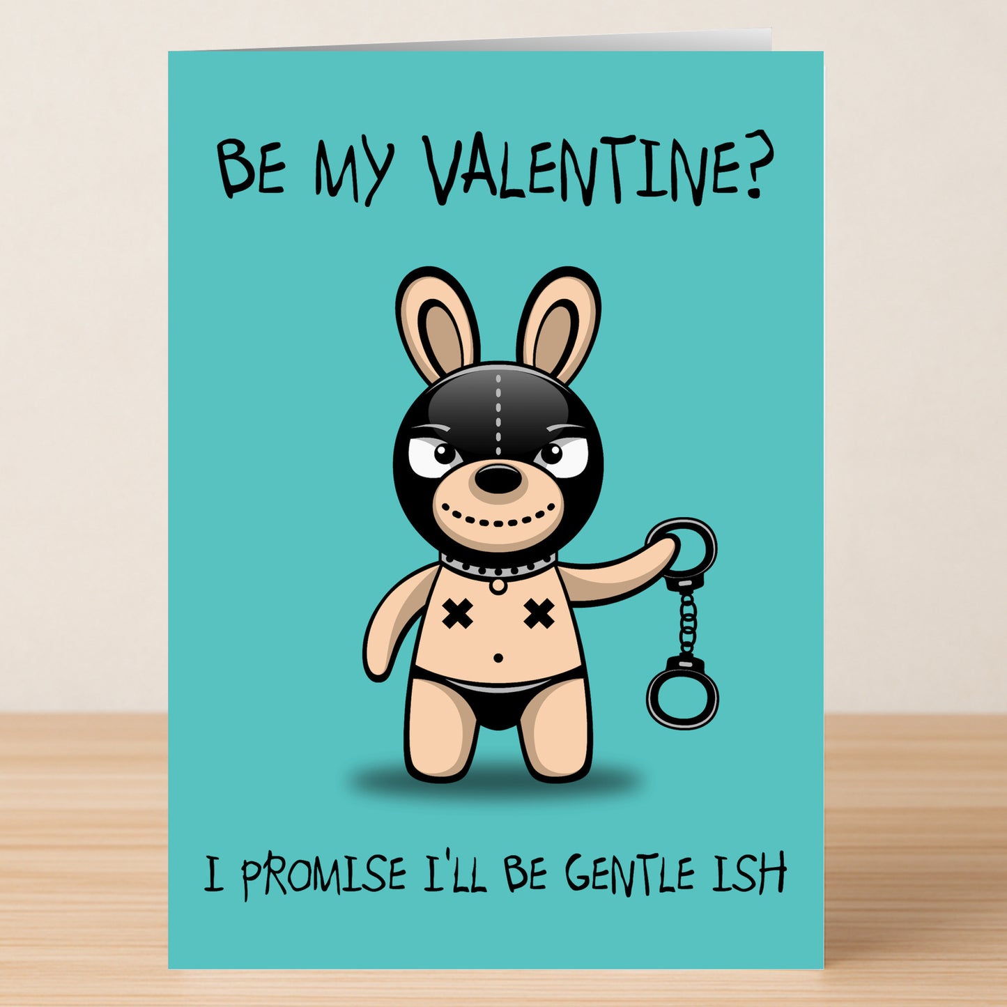 The Gentle Ish Rude Valentine’s Card by Twisted Gifts features a cartoon bunny in a bondage mask with handcuffs and the witty message, "Be my Valentine? I promise I'll be gentle ish." Perfect for sarcastic Valentine's greetings.