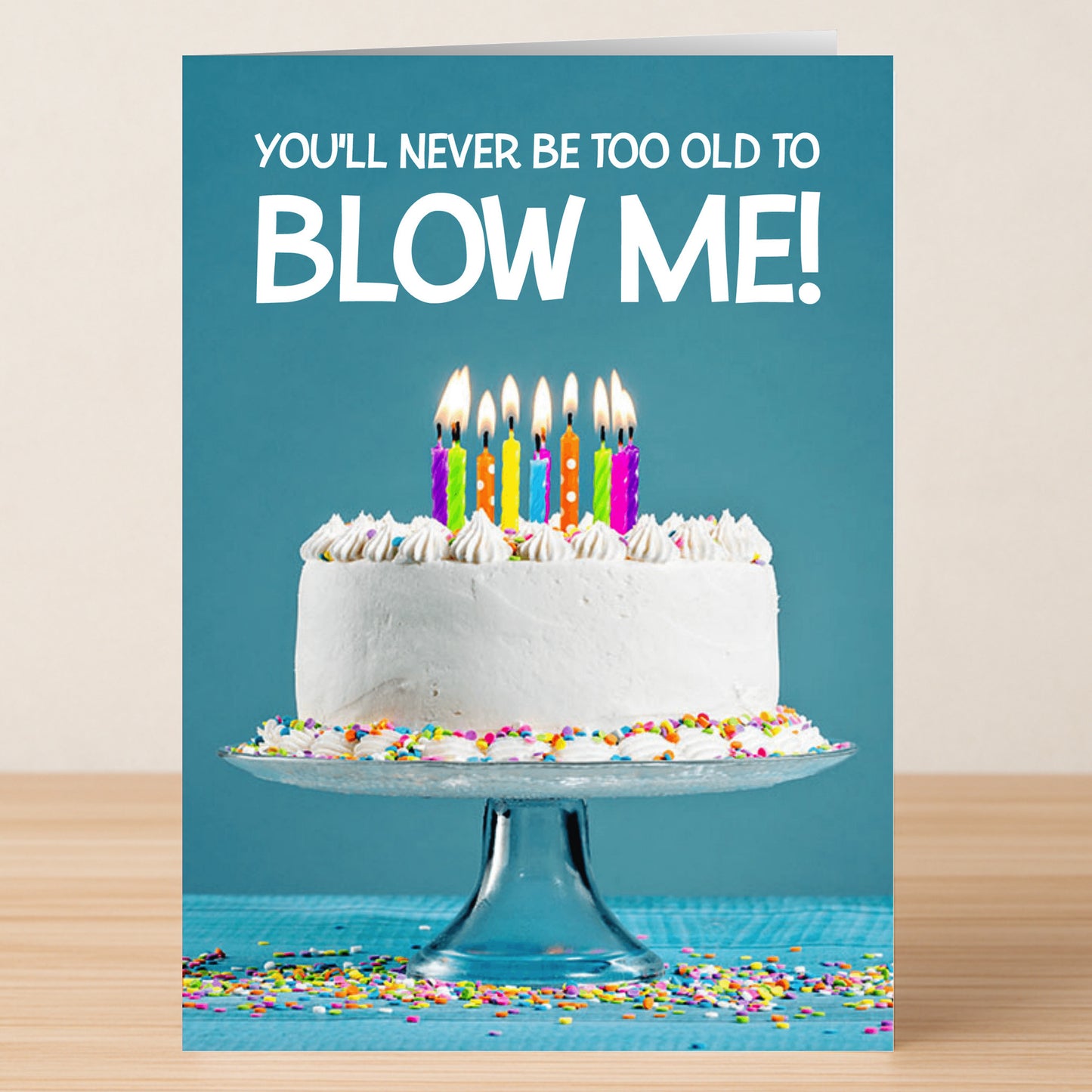The Blow Me – Rude Birthday Card by Twisted Gifts shows a white cake with rainbow candles and sprinkles on a glass stand. It reads, "YOU'LL NEVER BE TOO OLD TO BLOW ME!"—a hilarious pick for fans of offensive birthday cards.