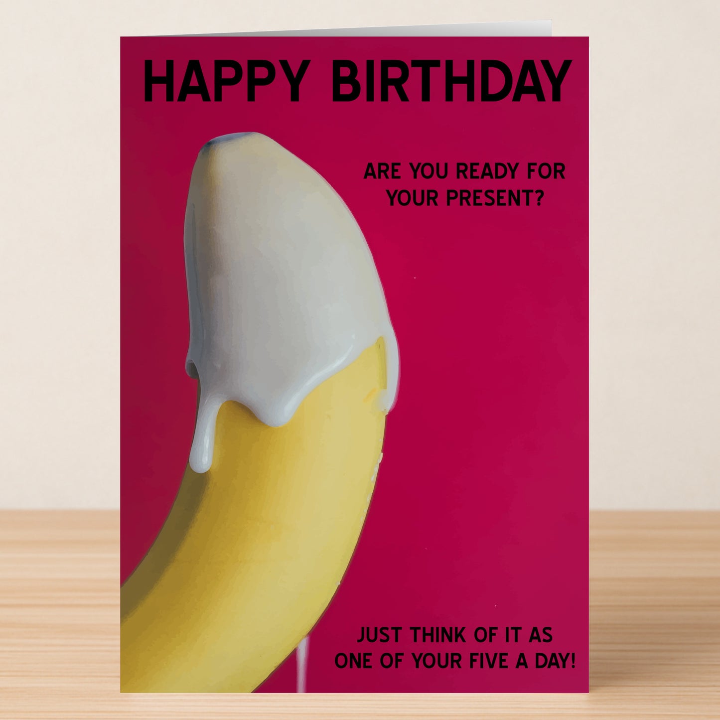 The Five A Day – Rude Birthday Card by Twisted Gifts features a banana with white icing on a pink background and the message: "HAPPY BIRTHDAY. ARE YOU READY FOR YOUR PRESENT? JUST THINK OF IT AS ONE OF YOUR FIVE A DAY!.